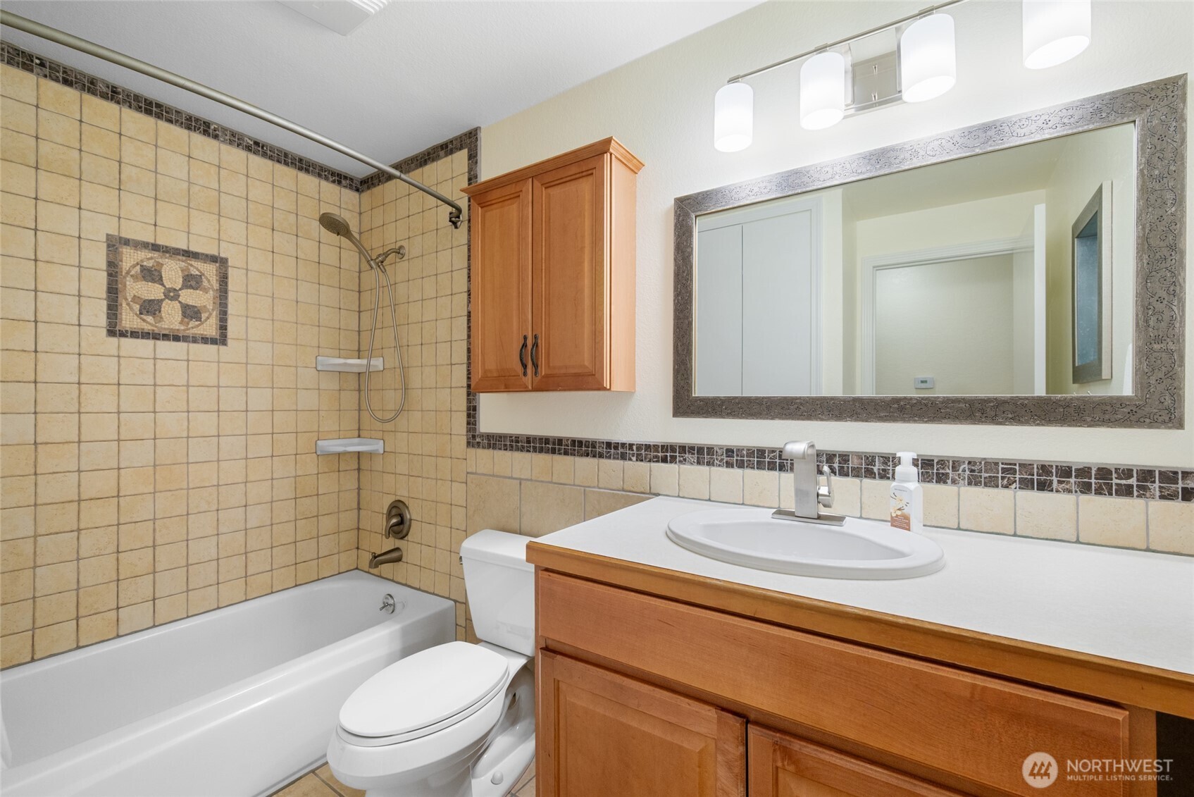 This lower-level bathroom offers warmth and comfort with its generous vanity, soft lighting, and stylish tile insets.