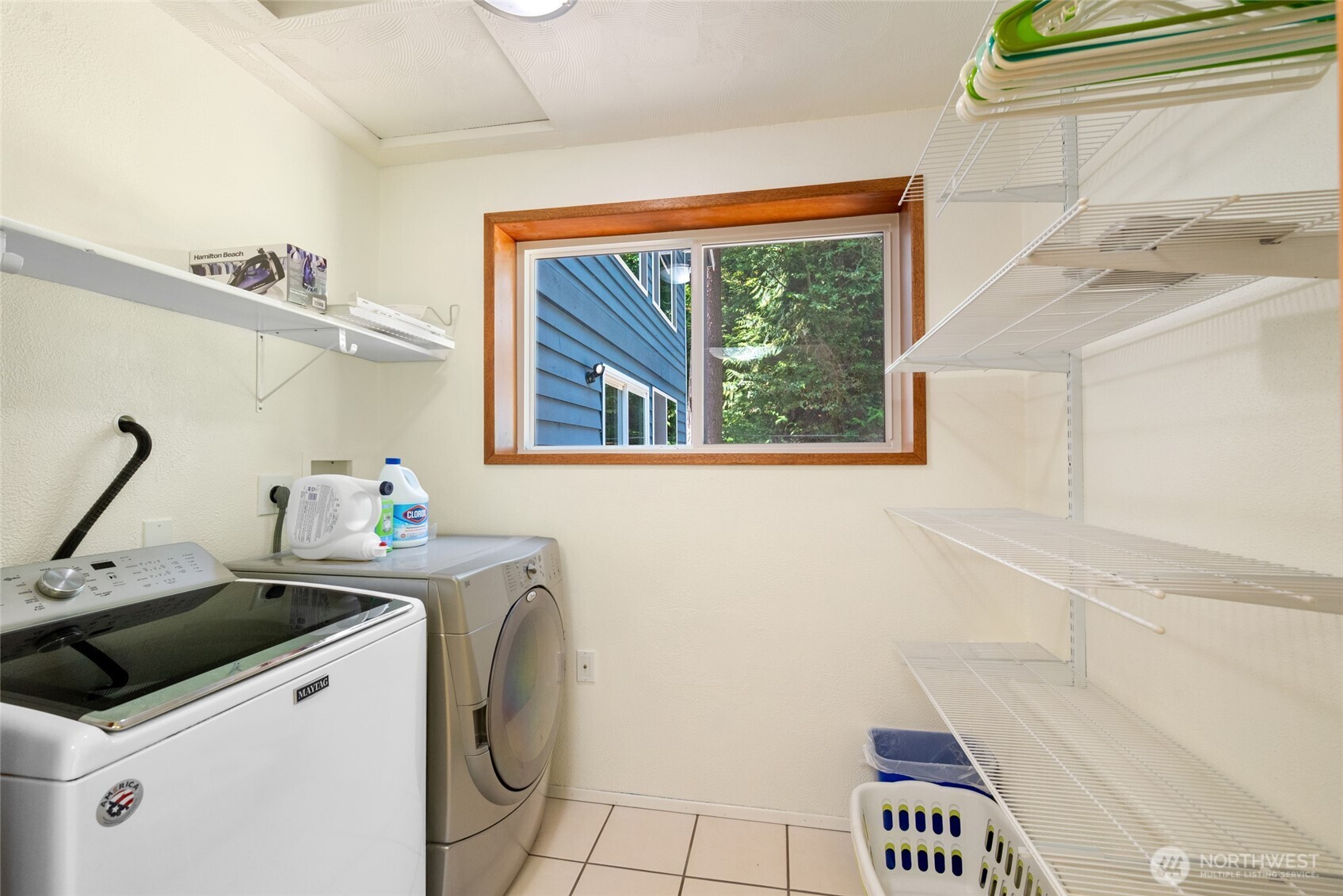 Dedicated laundry space with utility sink, full-size washer & dryer, and built-in shelving for easy organization—bright, efficient, and practical.