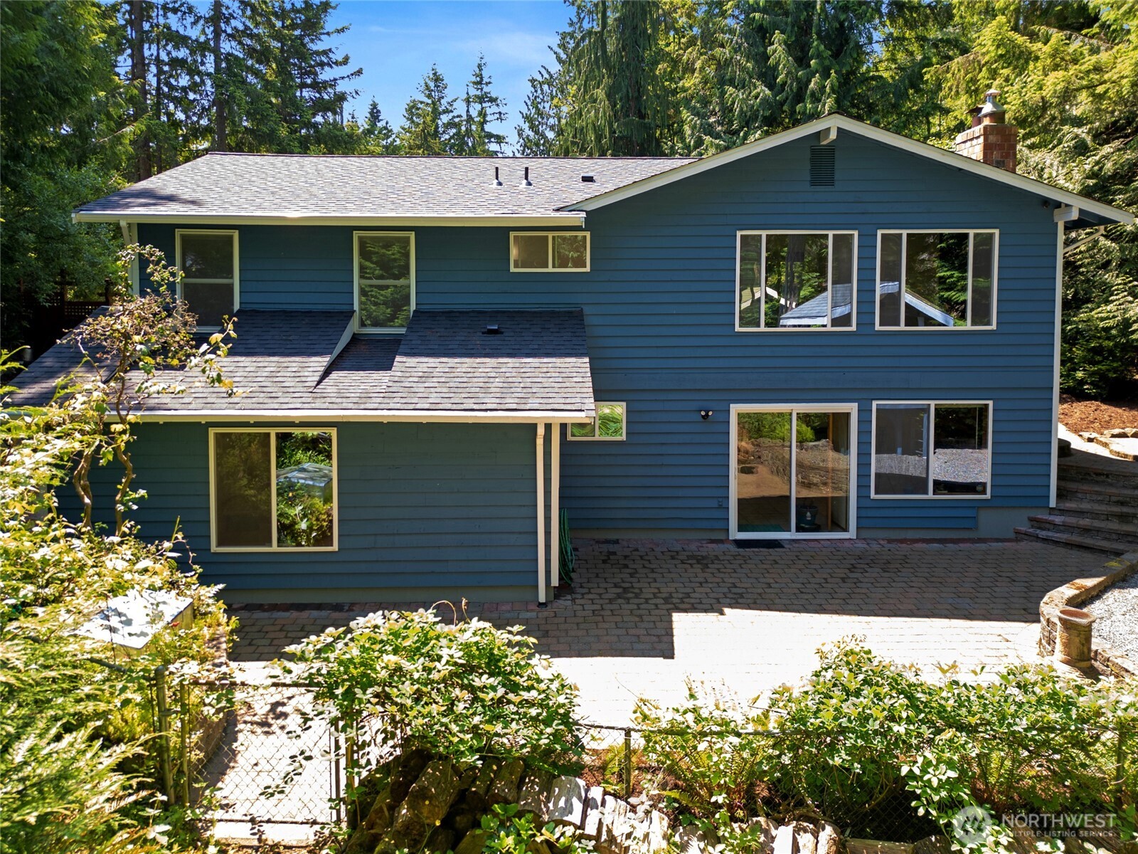 The home’s back exterior showcases its thoughtful layout with large windows across both levels, offering forest views and seamless indoor-outdoor flow.