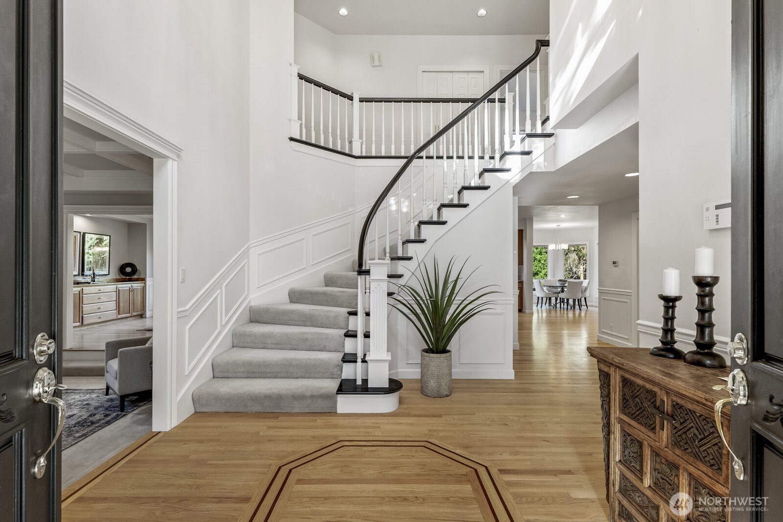 Impressive 2 story wainscoted foyer with an elegant curved bridal stairway and hardwood floor with walnut inlay.
