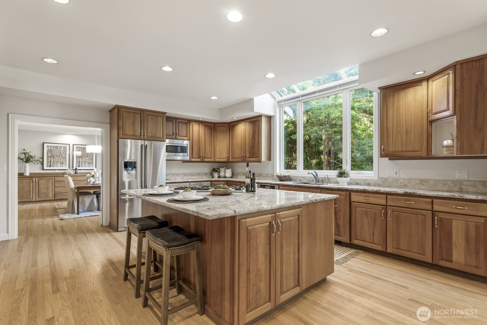 Updated kitchen with stainless steel Wolf double ovens, 5 burner Wolf gas stove, large center island with bar seating.