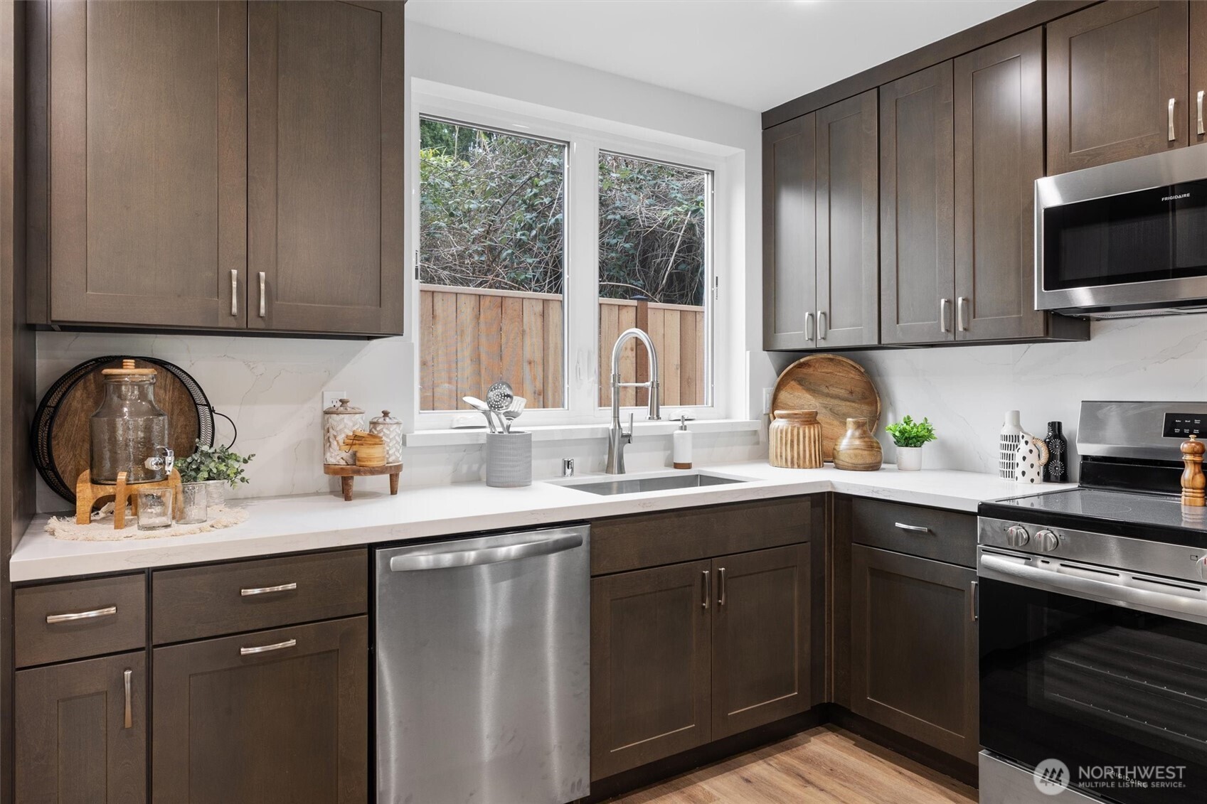 A deep under-mount sink sits below dual windows, filling the workspace with natural light and outdoor views.