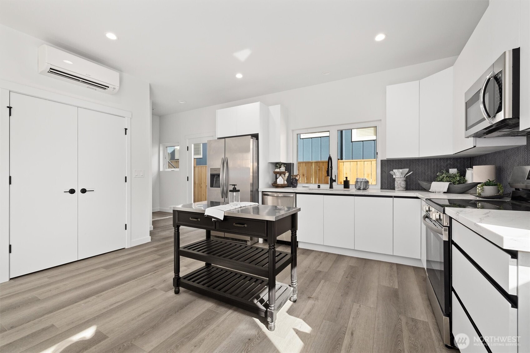 Dual windows and elegant black herringbone backsplash highlight the kitchen’s sophisticated design and natural light flow.
