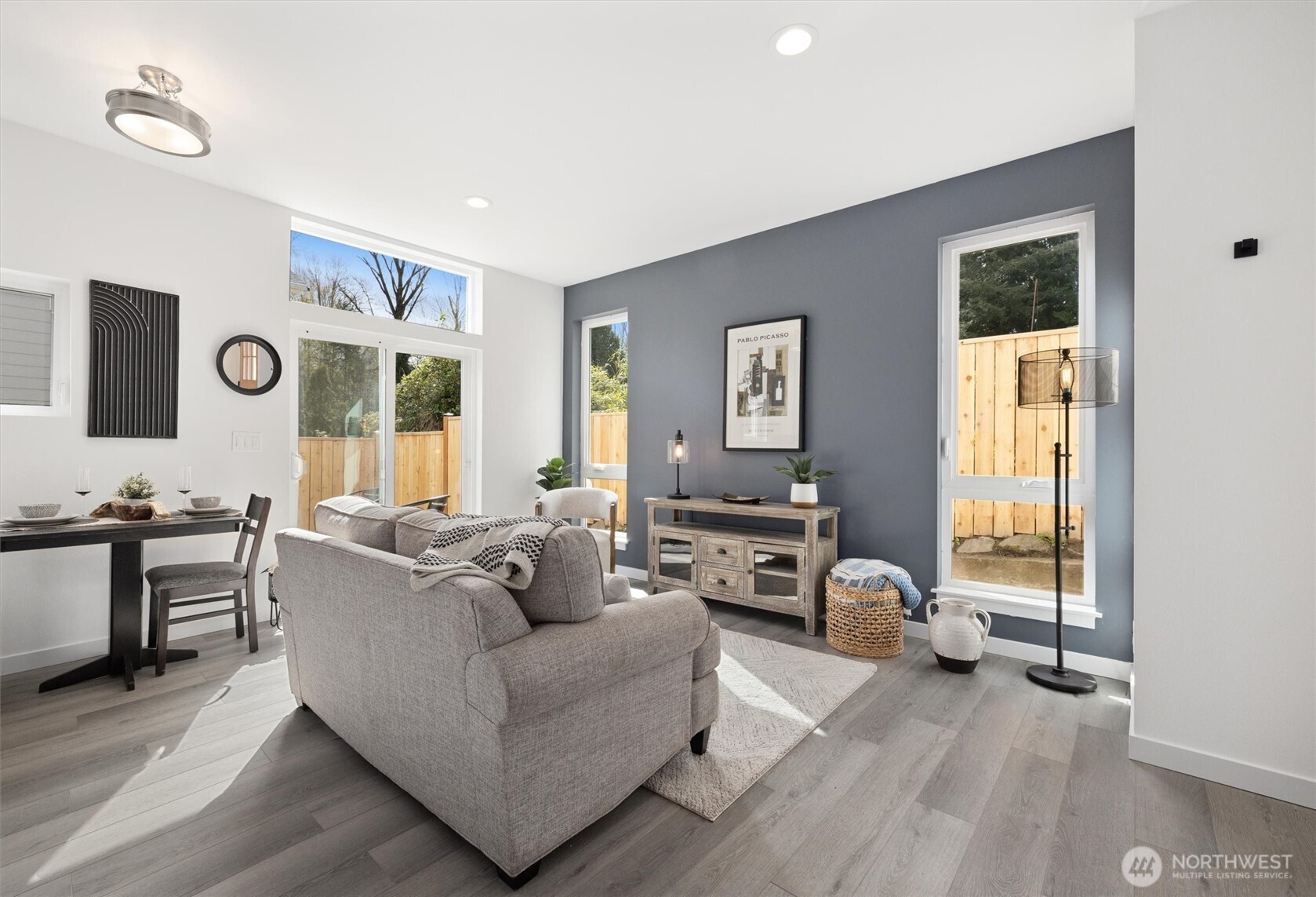 A cozy yet refined living room offers tall windows, a feature accent wall, and direct patio access for everyday comfort and entertaining.