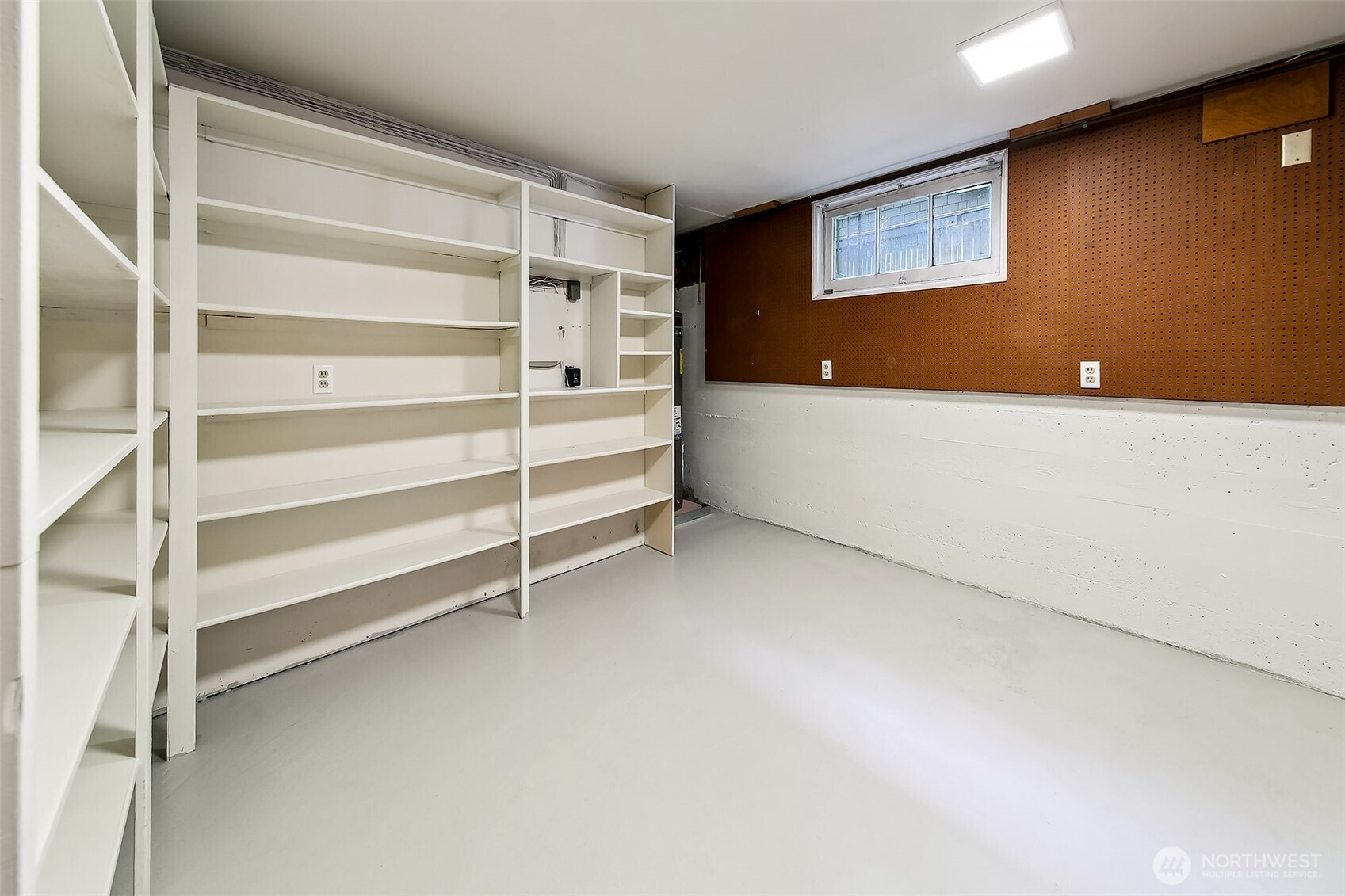 Generous storage/mechanical room with wall-to-wall shelving and high ceilings—perfect for seasonal gear, tools, or extra household provisions.