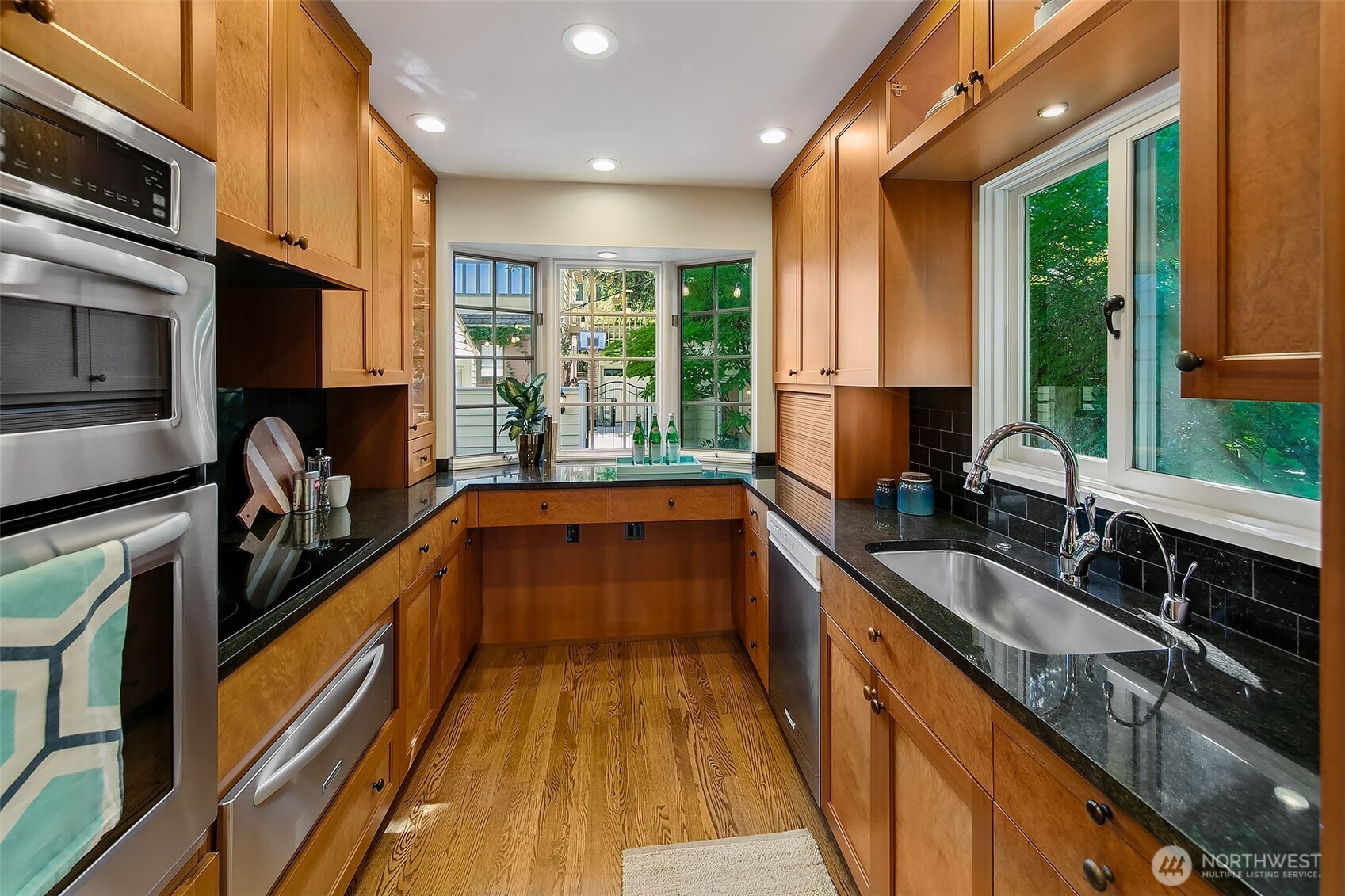 Chef’s kitchen showcases custom burl walnut cabinetry, integrated double ovens, and bay-window views—seamlessly uniting traditional millwork with modern functionality.
