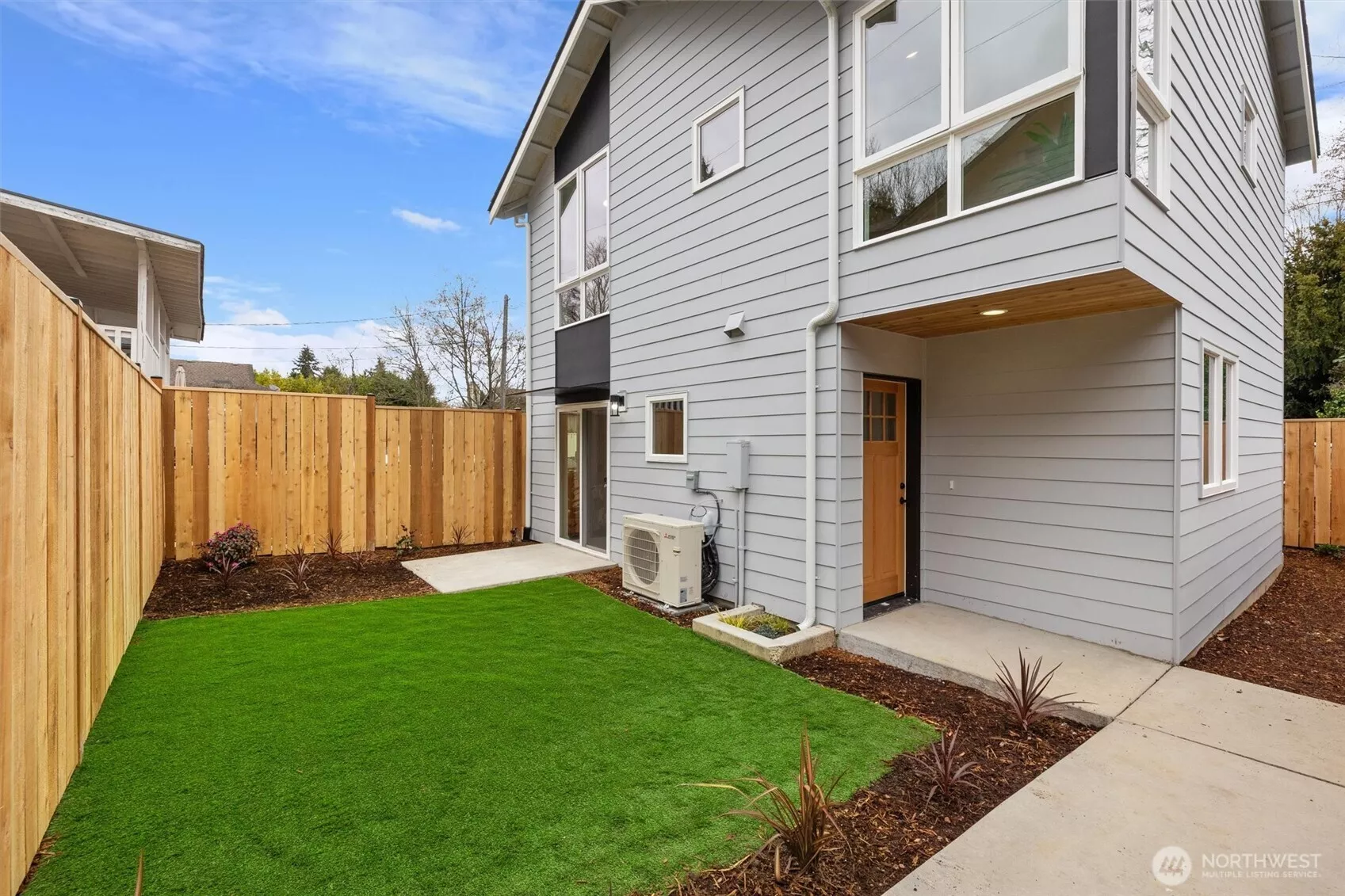 A fully fenced backyard with fresh landscaping and synthetic turf offers low-maintenance outdoor enjoyment.