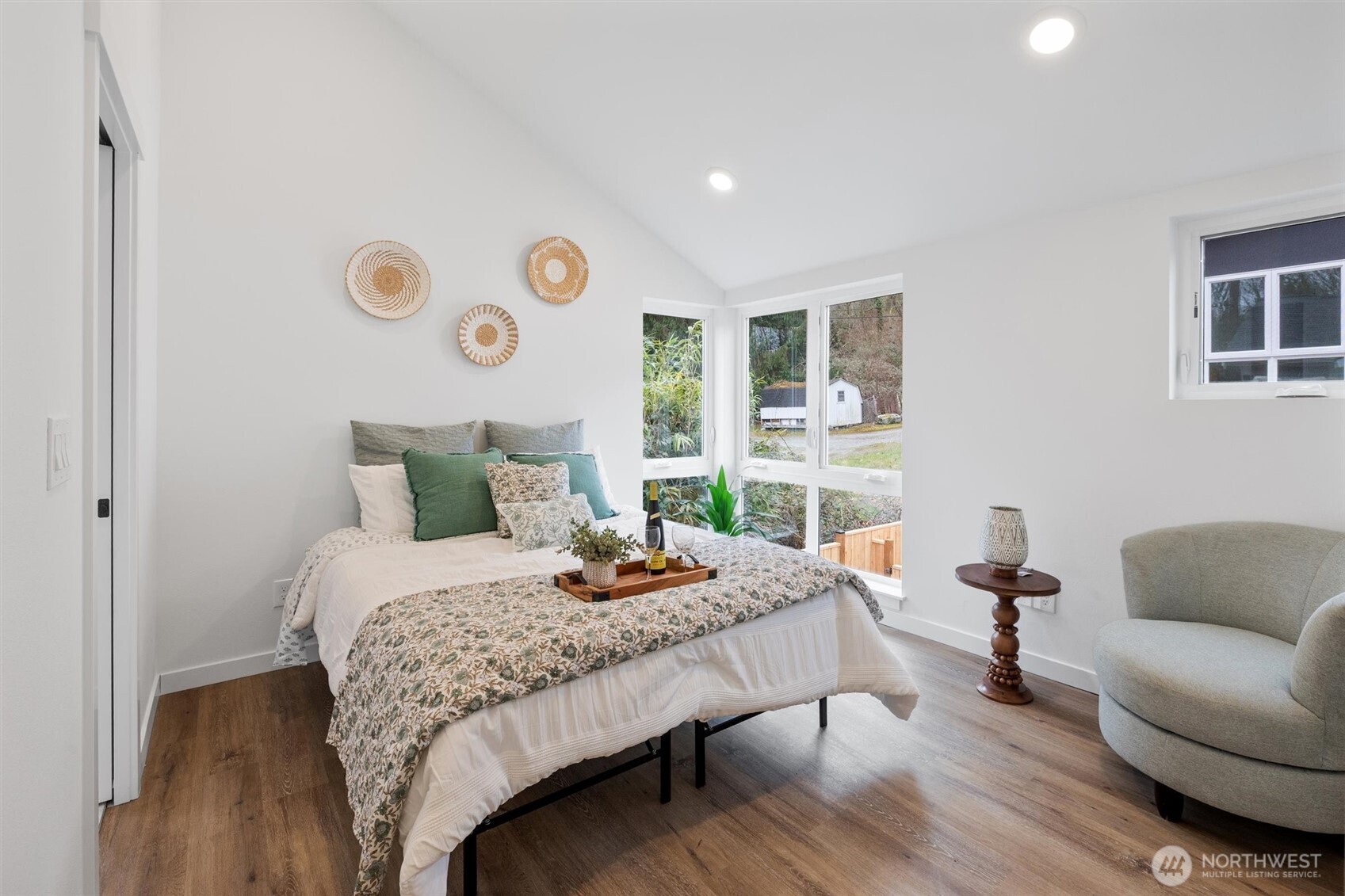 Vaulted ceilings and a wall of corner windows bathe the primary bedroom in soft natural light.