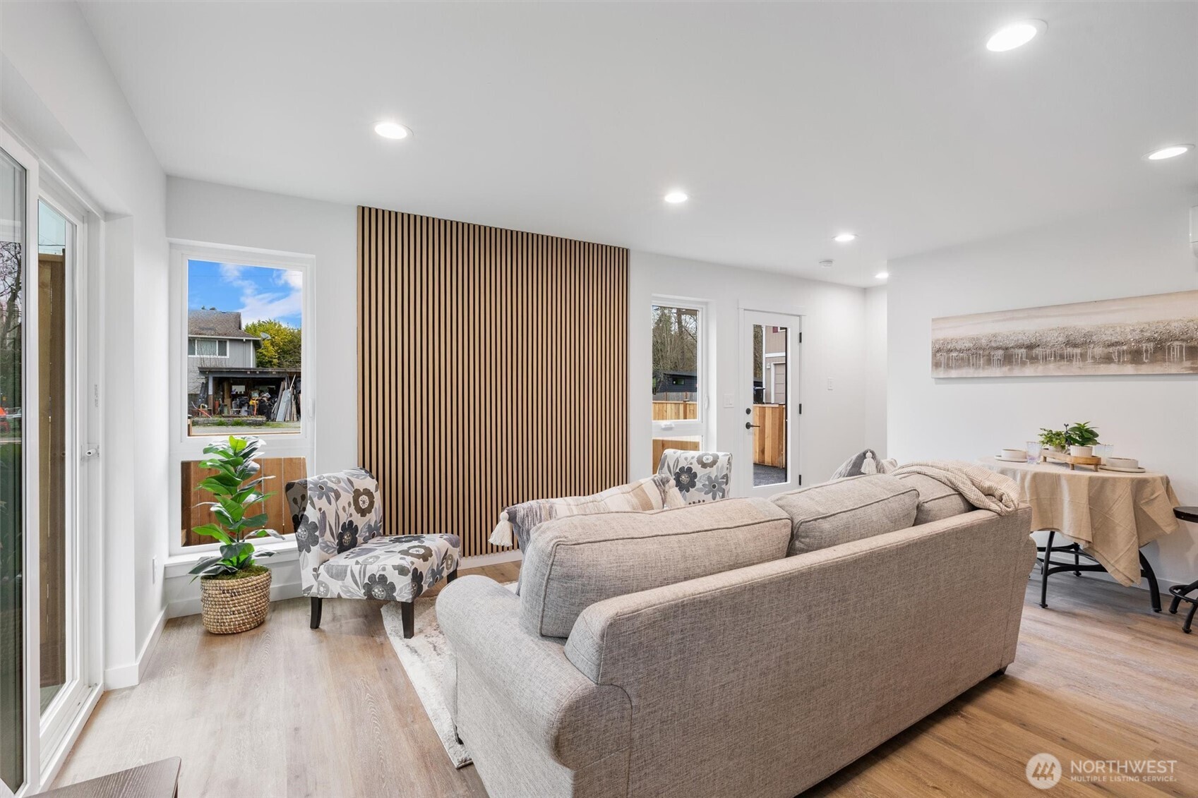 A sleek wood-slat accent wall anchors the bright and airy living room, enhanced by large picture windows.