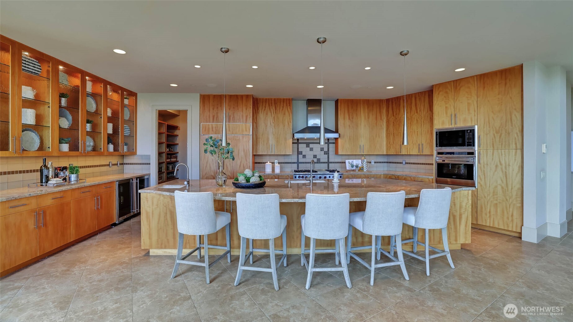 The spacious chef’s kitchen is a vision of elegance and functionality, boasting an oversized island, top-of-the-line Subzero and Wolf appliances, and abundant Tigerwood cabinetry.