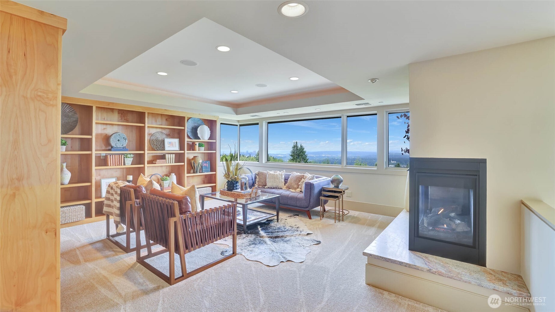 Upper-level, wide-open hallway leads to a captivating library with walls of shelves for books and collectibles and cozy gas fireplace.