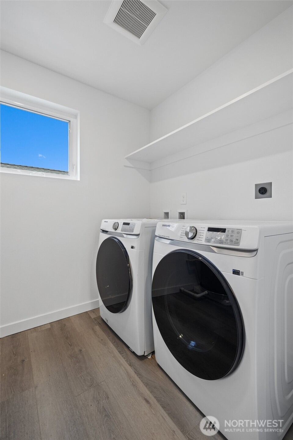 A dedicated laundry room includes modern Samsung appliances, built-in shelving, and a window for natural light.