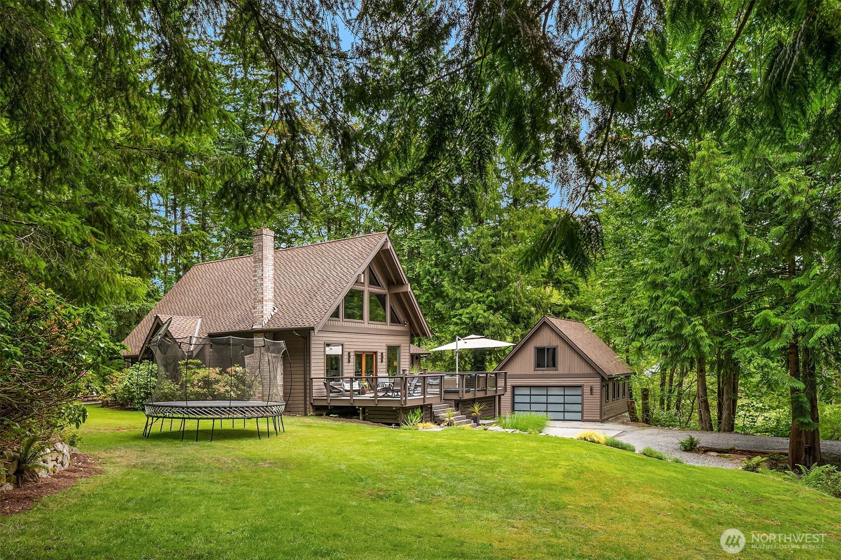 This home features new landscaping and is framed by towering fir trees.