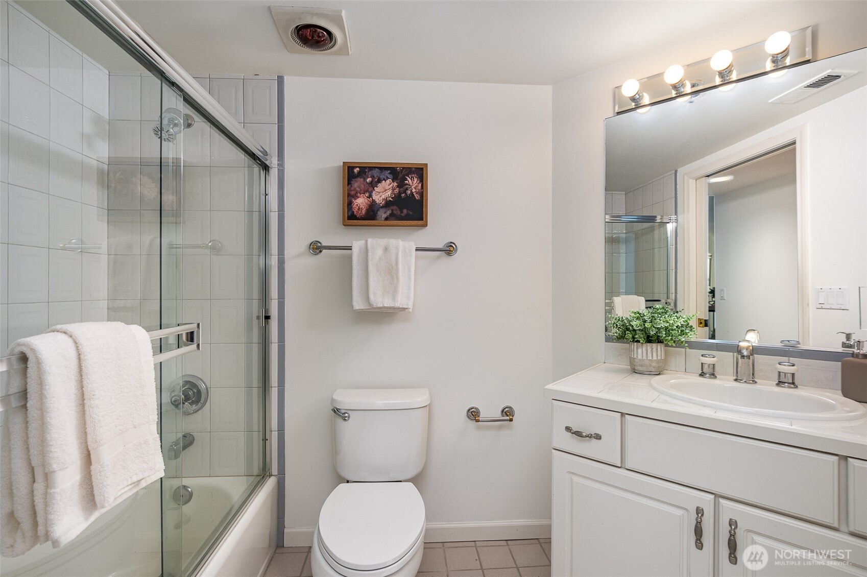 The second full bathroom is crisp and clean, featuring a shower/tub combo with sliding glass doors, a wide vanity with storage, and classic tile finishes.