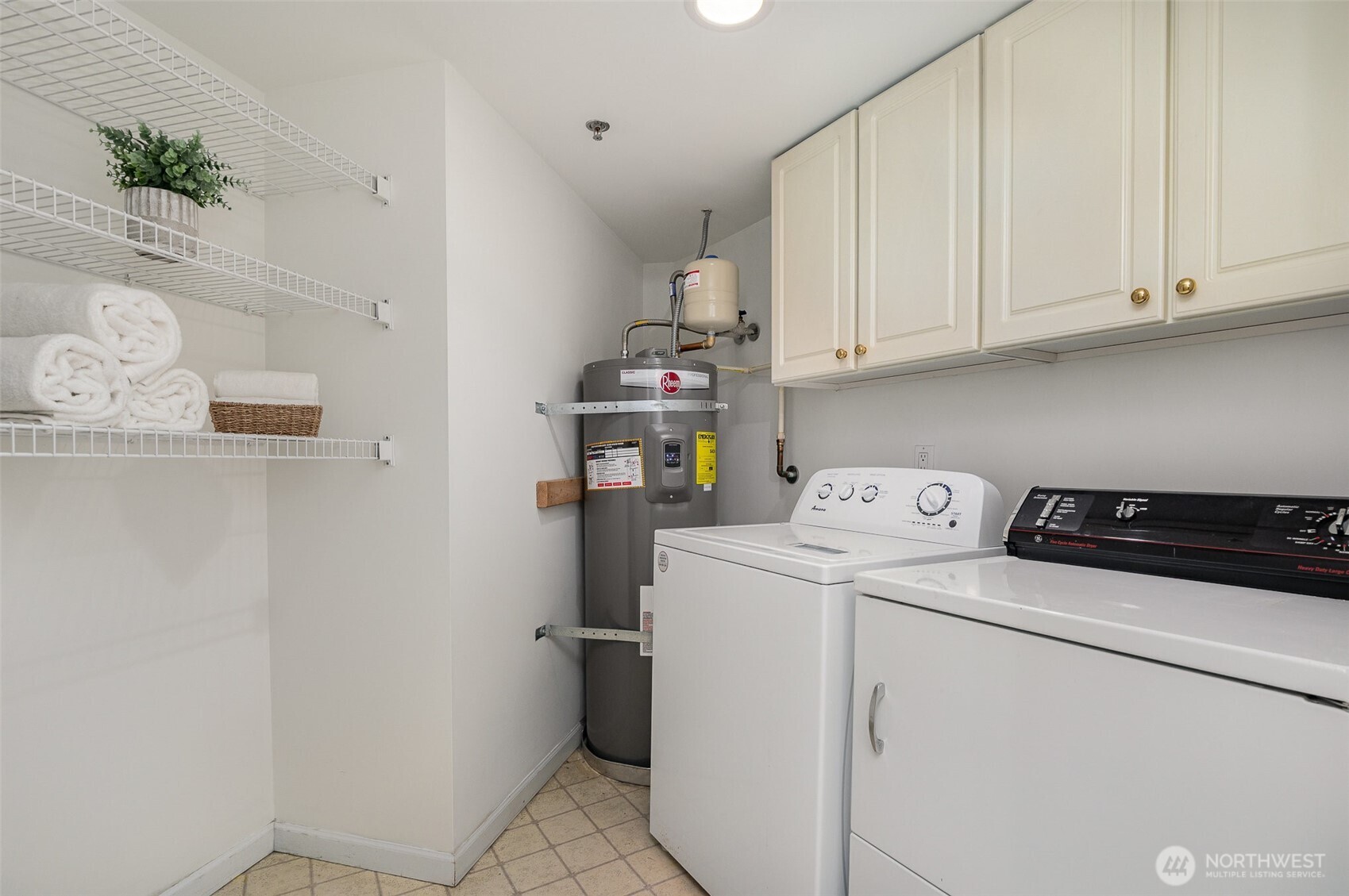 The spacious laundry room offers exceptional functionality with upper cabinets, wall-mounted shelving—plenty of storage to keep everything organized.