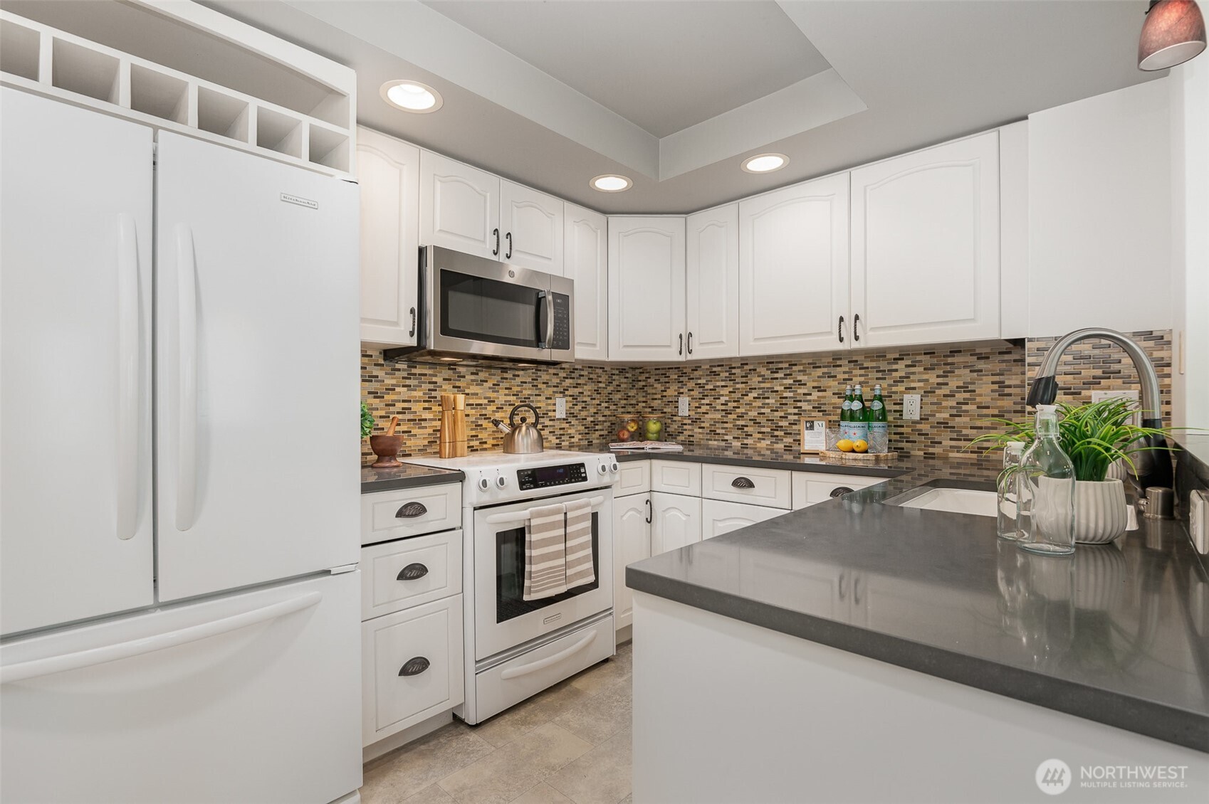 Kitchen offers timeless white cabinetry, quartz countertops, and a stylish mosaic tile backsplash—bringing both charm and functionality to the heart of the home.