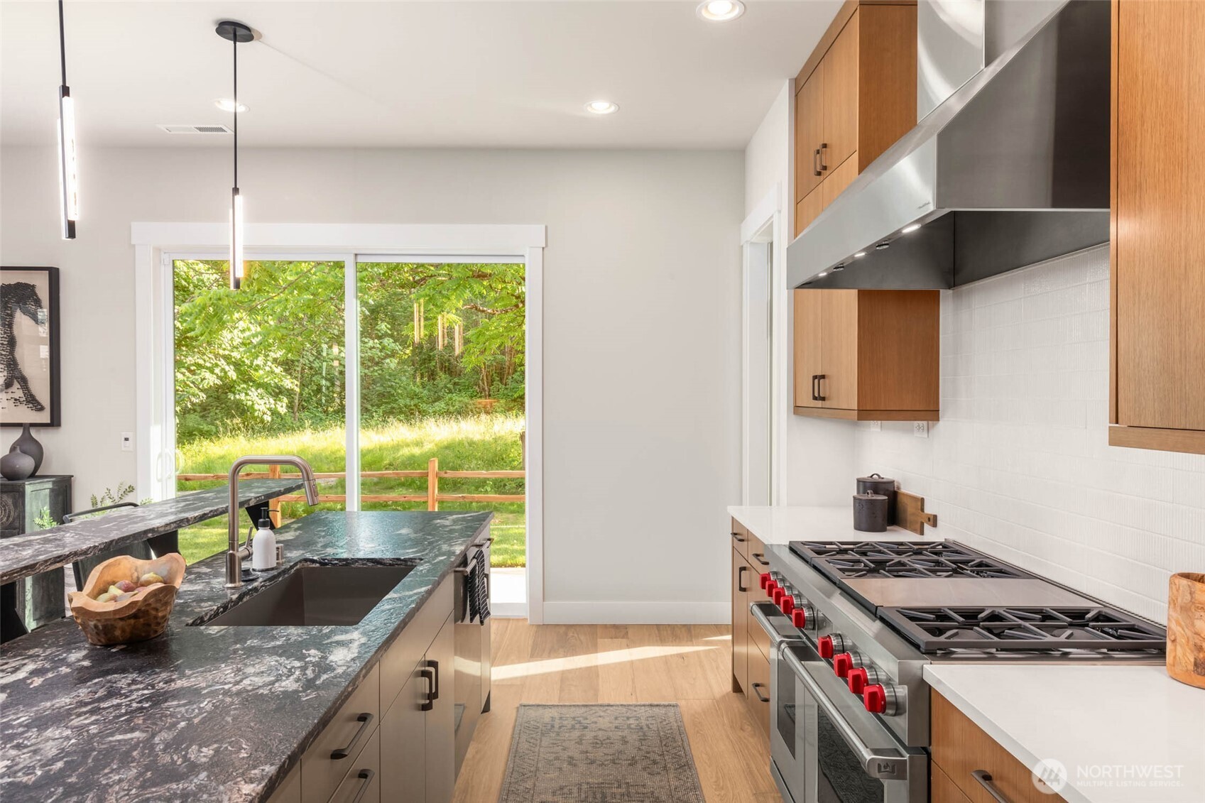 Island accented by painted cabinets and quartz counters while upper and lower surround custom cabinets are finished in a rift oak and topped with secondary quartz slab counters