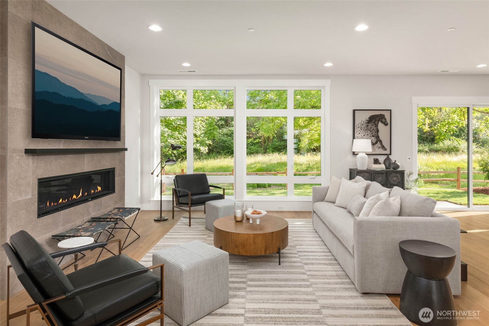 Great room flooded with natural light through floor to ceiling windows and 10 foot ceilings. Contemporary linear fireplace with full height tile surround frames the open concept living space