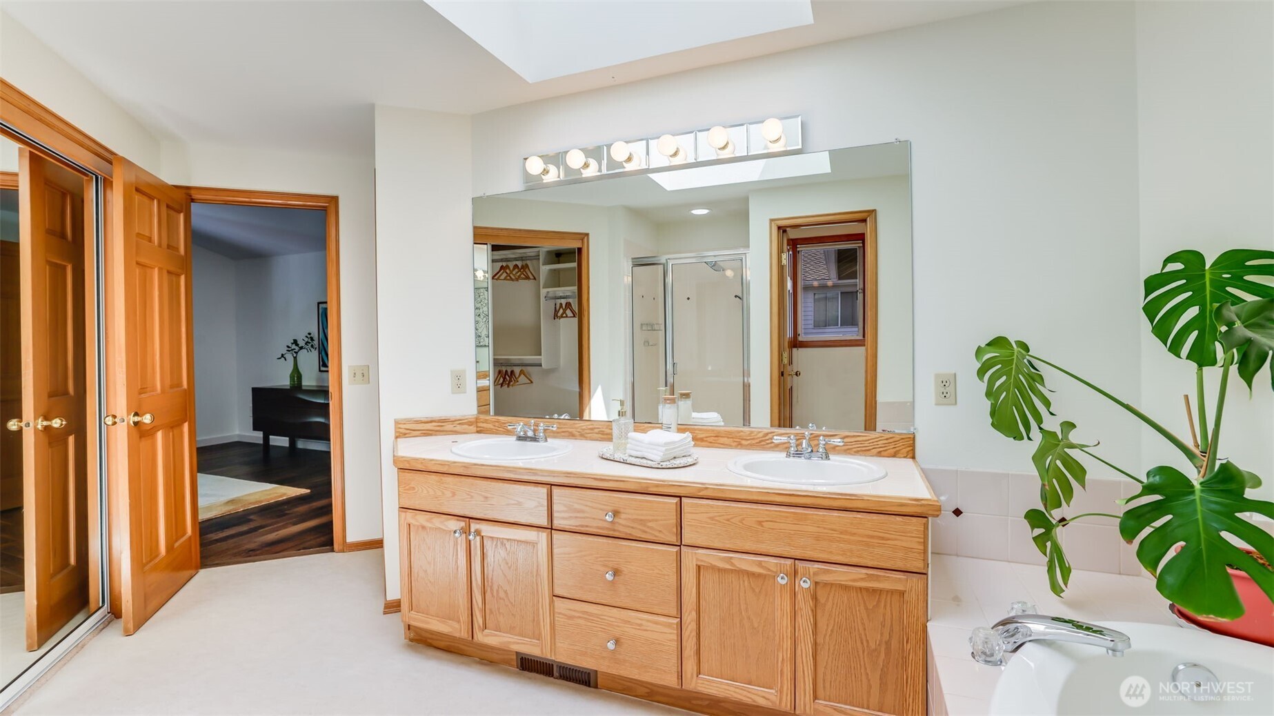 Attached to the primary bedroom, this en-suite offers dual vanities, oversized mirrors, and a walk-in closet with built in shelves, providing plenty of room for daily routines and storage with ease