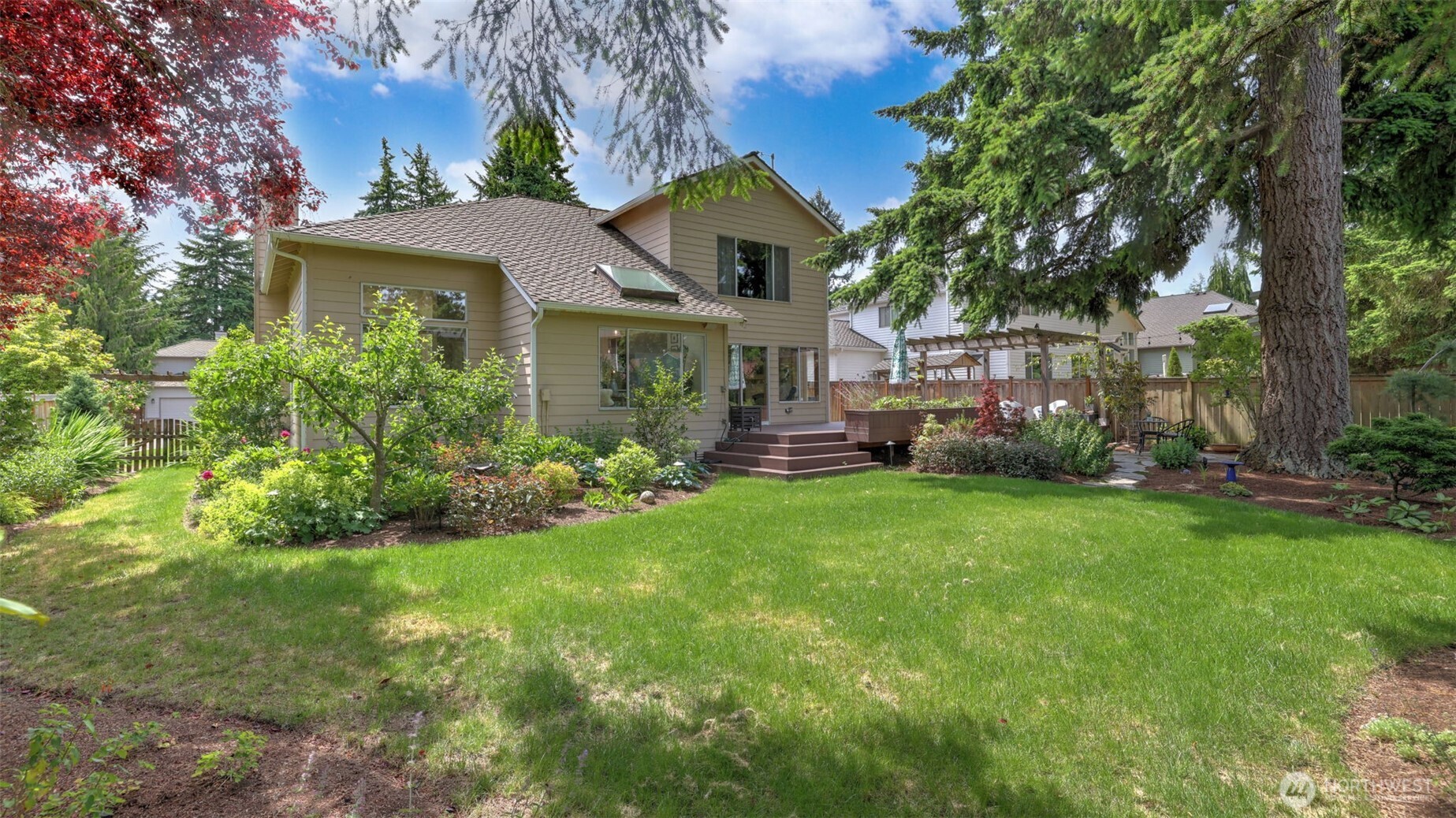 The fully enclosed backyard features an expansive lawn, perfect for hosting gatherings and events, while offering exceptional privacy amidst lush, verdant landscaping