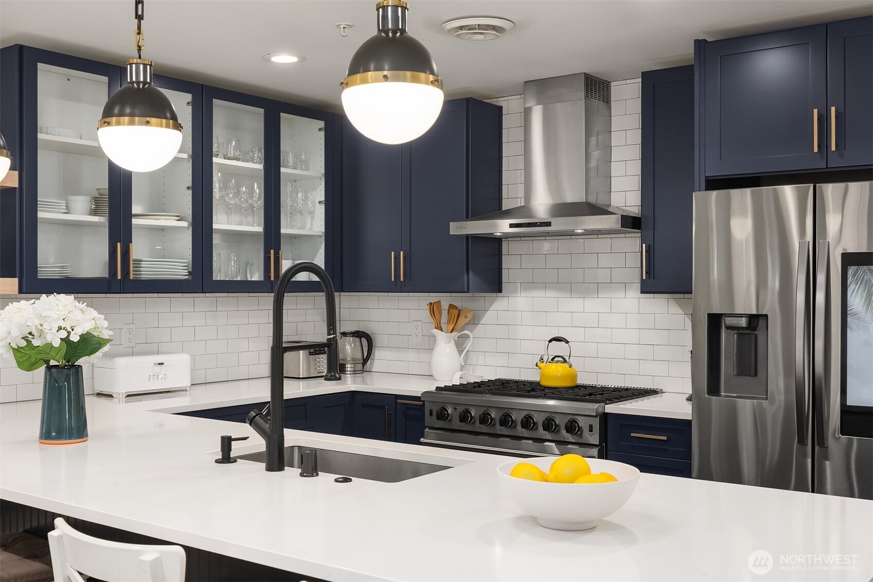 Design-forward kitchen with rich navy cabinetry, quartz counters, and commercial-grade appliances.