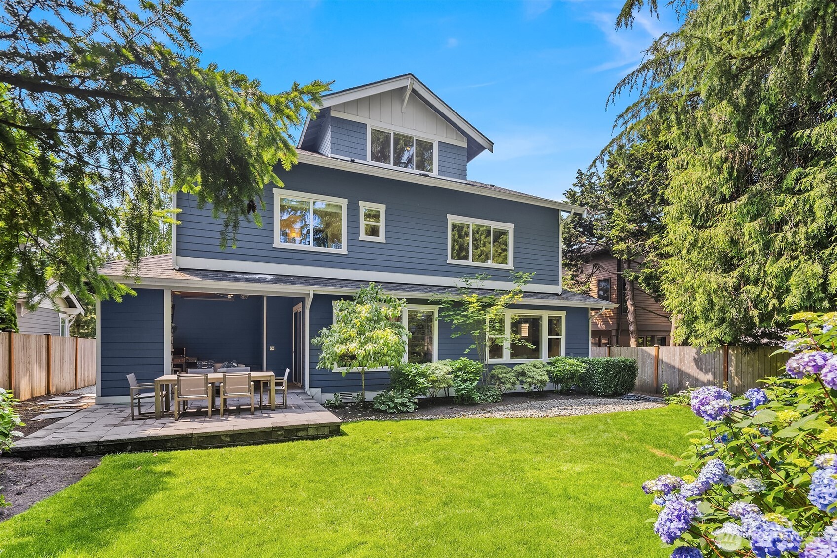 A picture-perfect Craftsman with covered patio, lush lawn, and flowering garden beds—this sunny backyard is an ideal extension of the home’s indoor-outdoor lifestyle.
