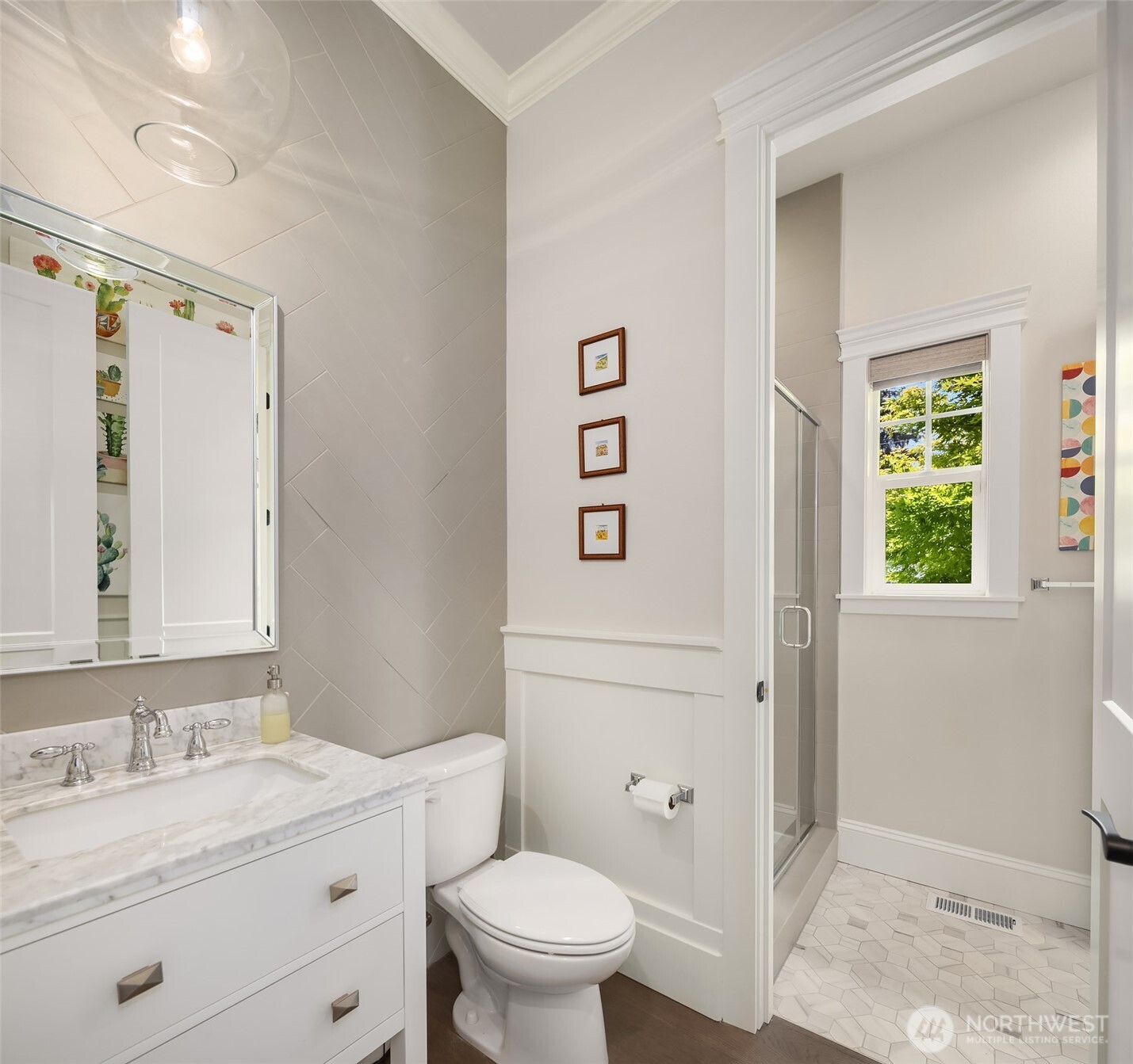 Thoughtfully designed main floor bath featuring a marble-topped vanity, stylish tilework, and a light-filled walk-in shower. Dual access from both the main living area and the adjacent bedroom allows for flexible use—easily functions as a powder room day-to-day, or opens up as a full guest bath when needed.