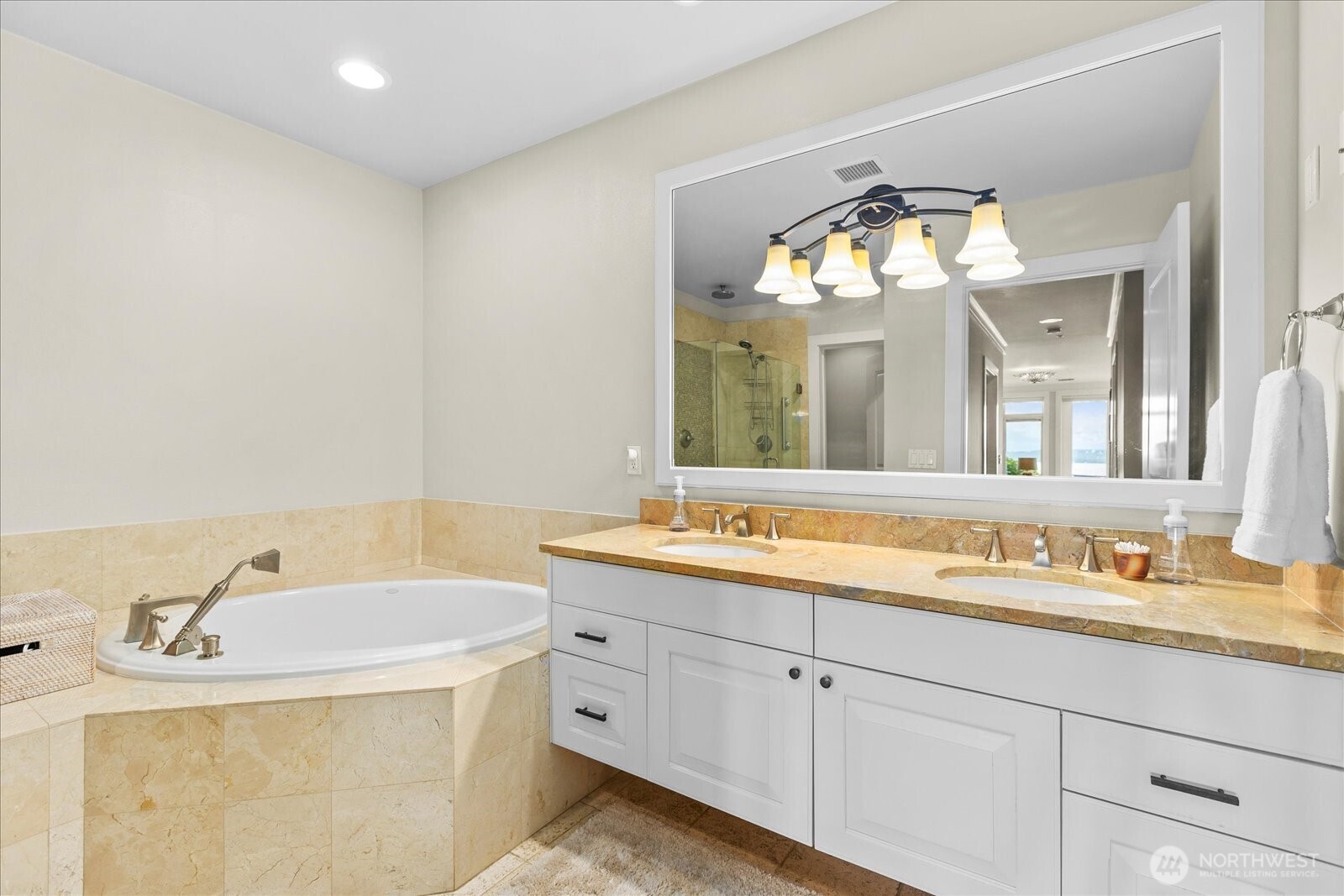 Ensuite 5 piece primary bath features dual sink vanity undermounted in marble counter tops, travertine floors, soaking tub and . . .
