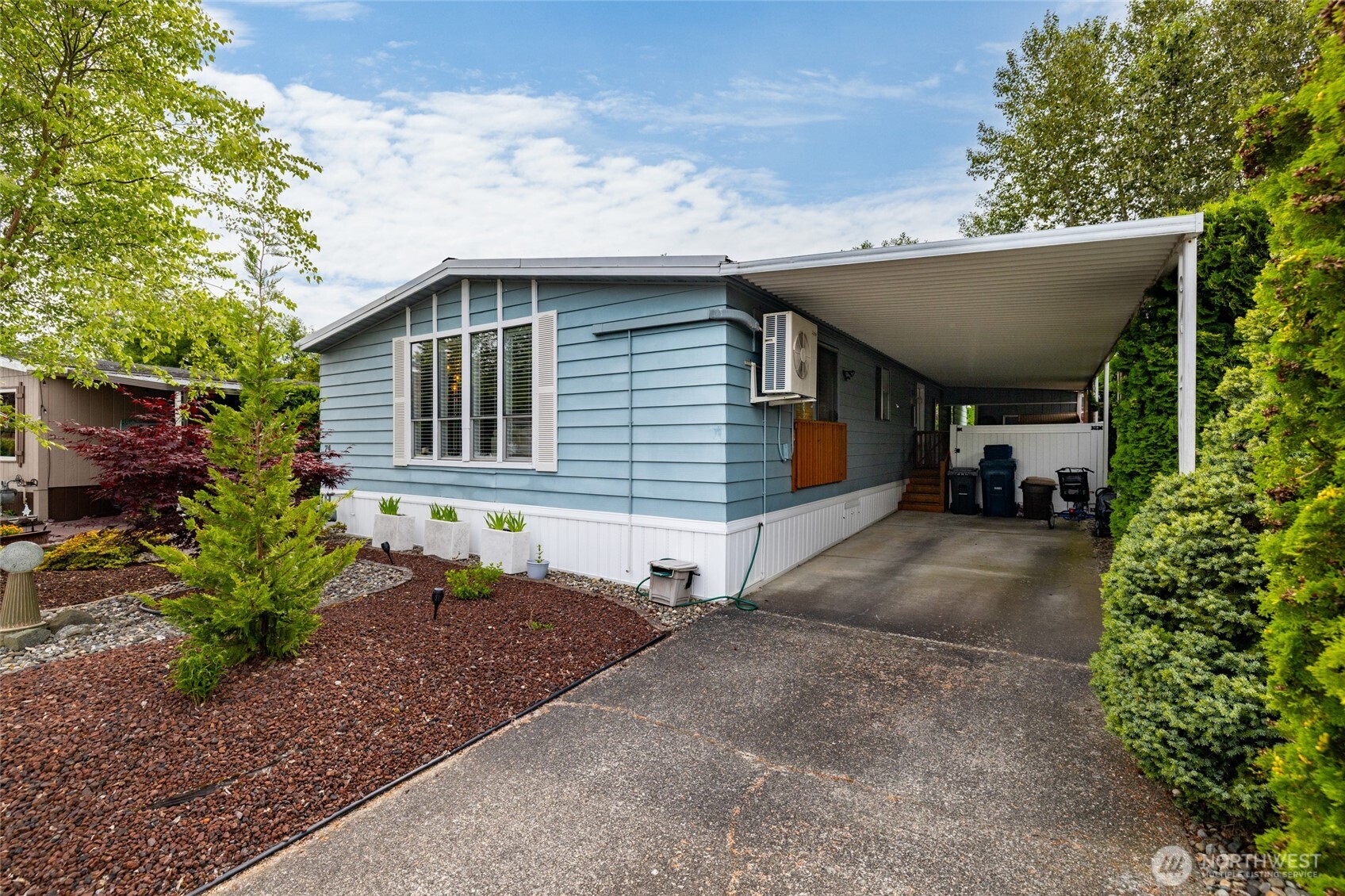Another view of the front, showing the clean carport and large storage shed behind it.