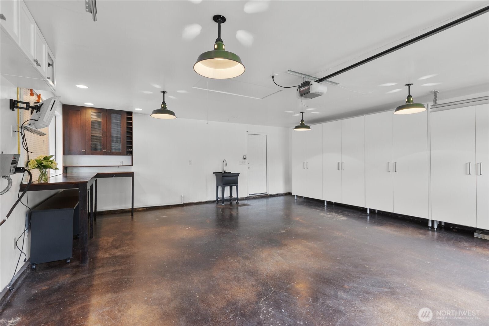 Garage has a utility sink, built-in storage and handsome sealed concrete flooring.