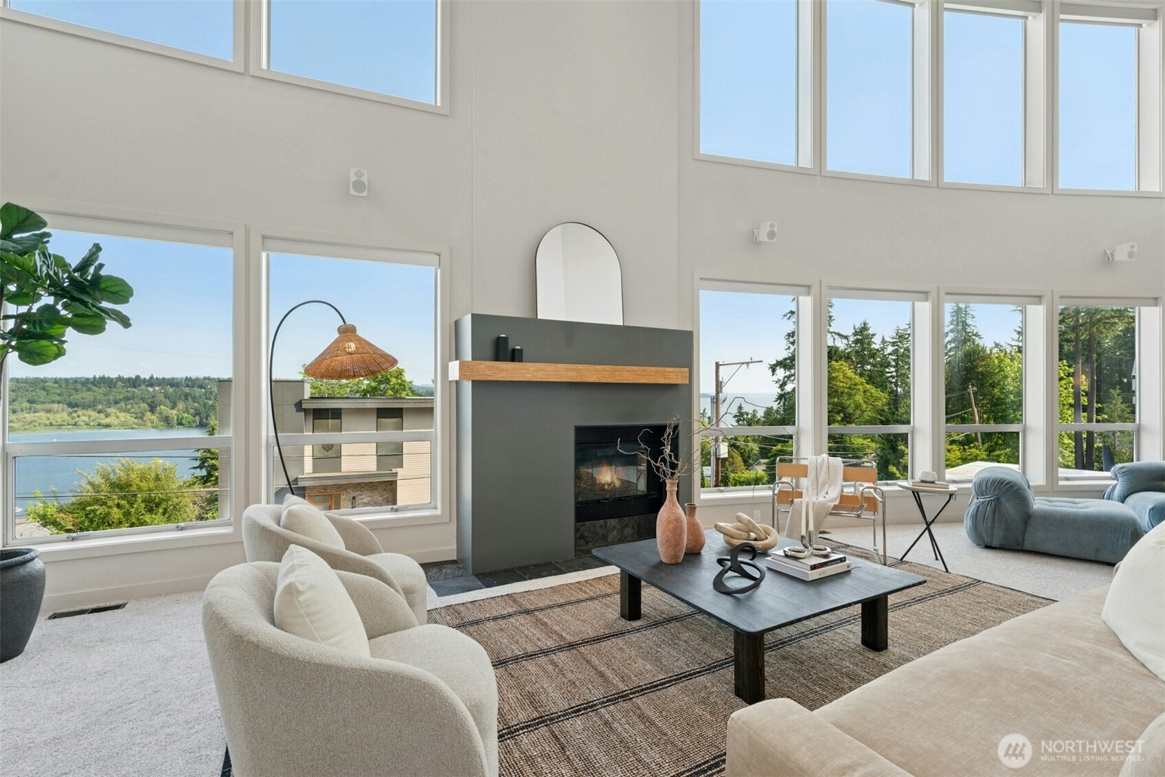 2 story living room with soaring ceilings & walls of glass framing the lake & mountain views beyond