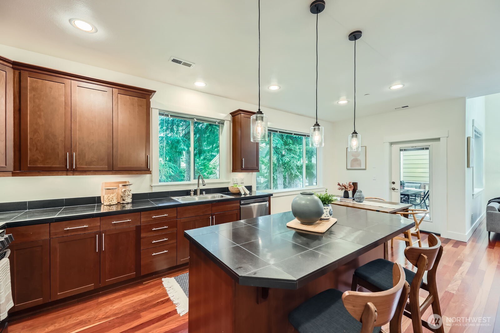 Sleek kitchen with large island / breakfast bar, dining area and door to covered deck.