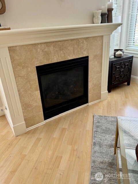 The light-filled living room has been tastefully remodeled with light hardwood floors, stone surround, gas fireplace and high ceilings.