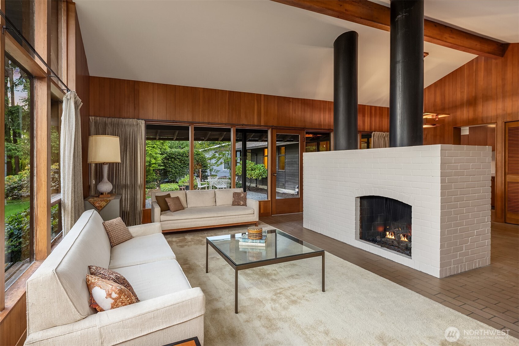 The central fireplace creates a gentle separation between dining and living room.