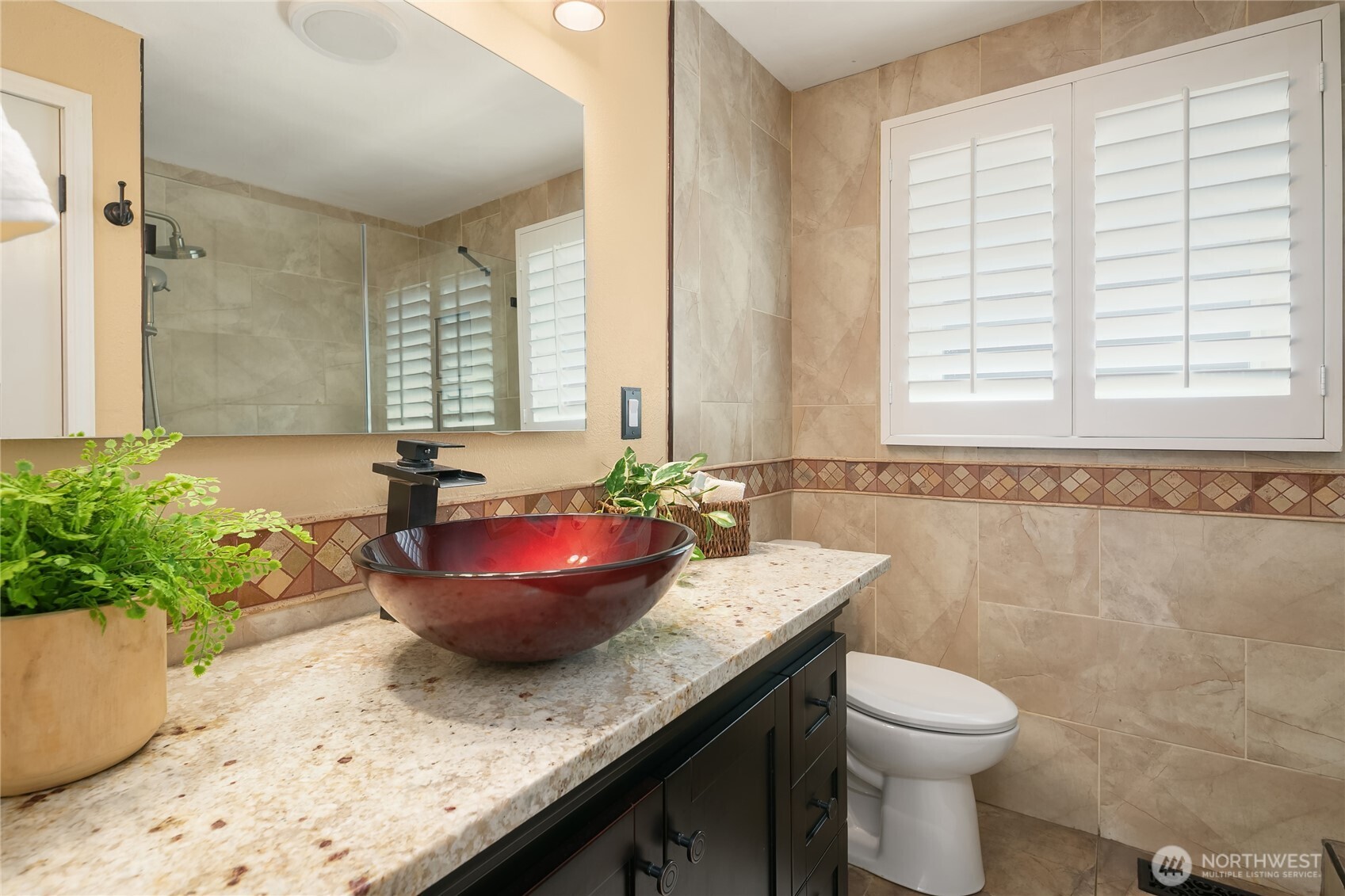 Beautifully remodeled bath featuring custom stone tile, plantation shutters.