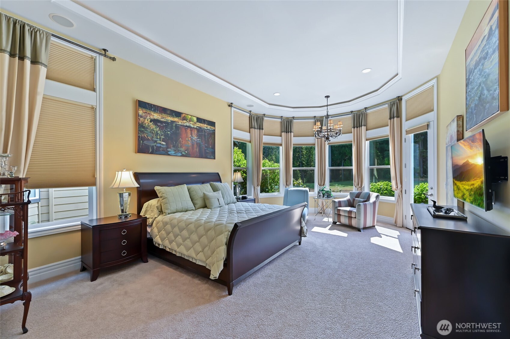 The primary bedroom has a bay seating area, a stunning coved ceiling, floor to ceiling draperies and shades, and, a door to the west facing deck.