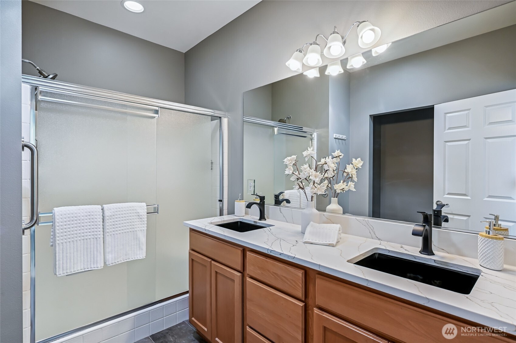 The primary bathroom has newer quartz counters, double under mount sinks and faucets set off by porcelain tile floorings. The step in shower has a seating bench and there is a private toilet room.