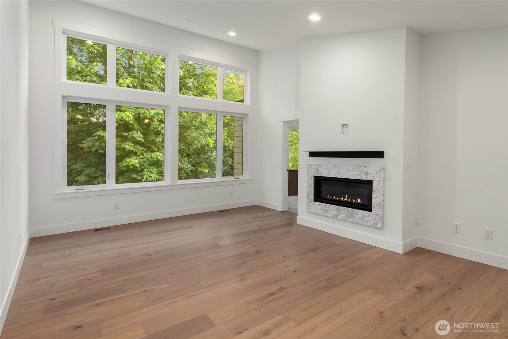 Absolutely stunning primary suite with soaring vaulted ceilings and wall of windows and linear fireplace with custom tile surround and mantle