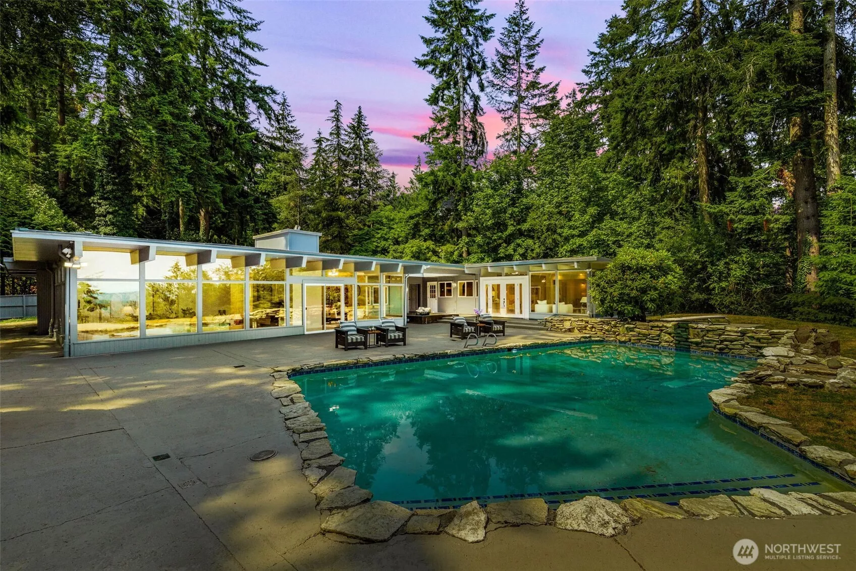 Mid-century modern home perched on Cougar Mountain, surrounded by nearly 2 acres of lush green landscaping with an in-ground pool, ideal for summer parties.