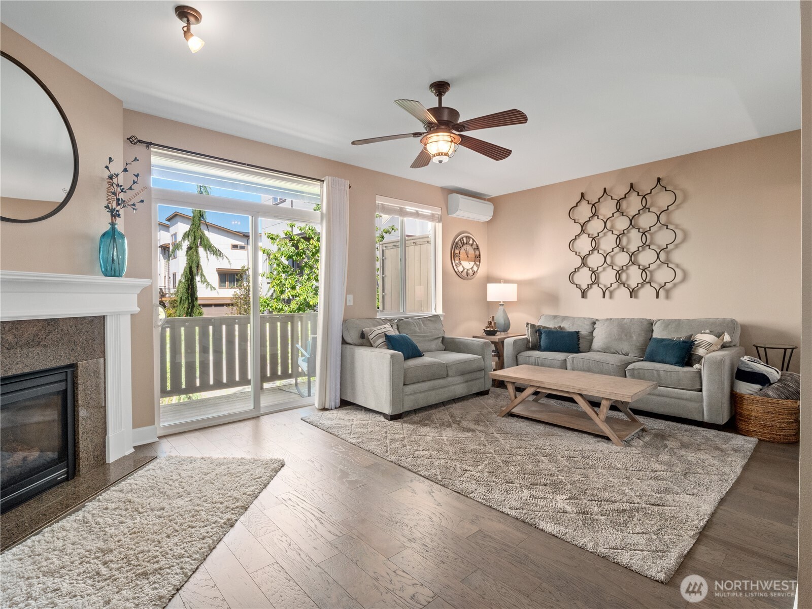 This inviting space features rich hardwood floors, a cozy gas fireplace with a classic white mantel, and large sliding glass doors that flood the room with natural light while offering access to a private balcony.