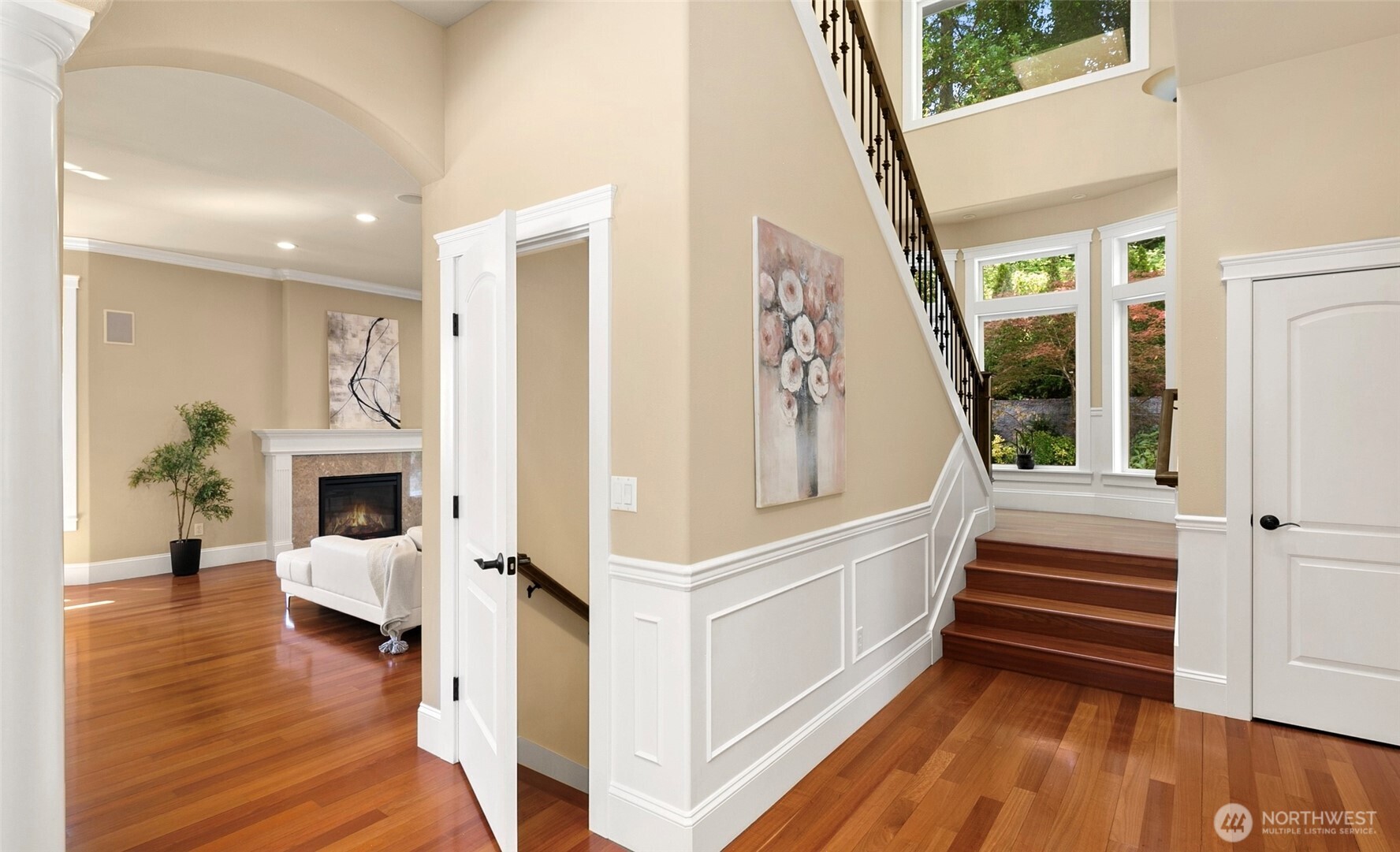 A stunning wrought-iron staircase is framed by beautiful picture windows, with a guest closet nestled in the corner and a discreet doorway beneath the stairs leading to the daylight basement.