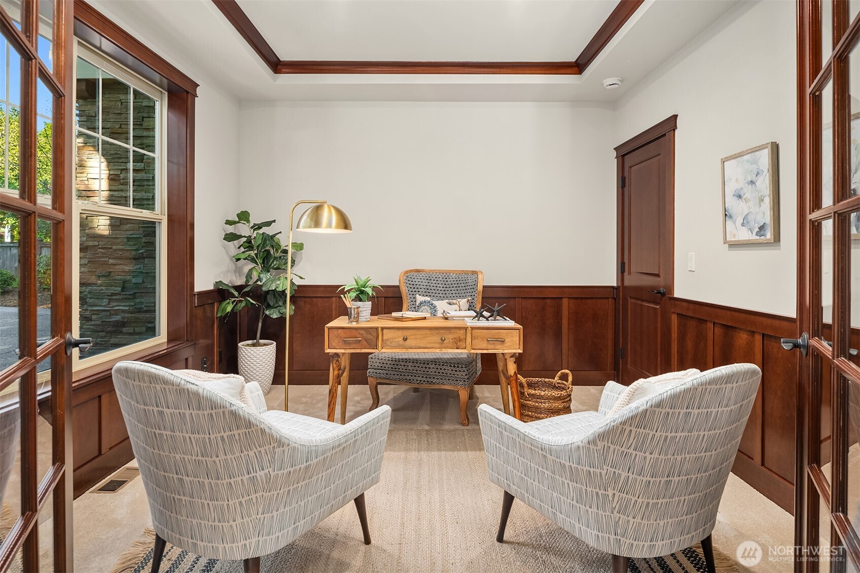 Divided light French doors open to Office with coffered ceiling and stained wood wainscoat