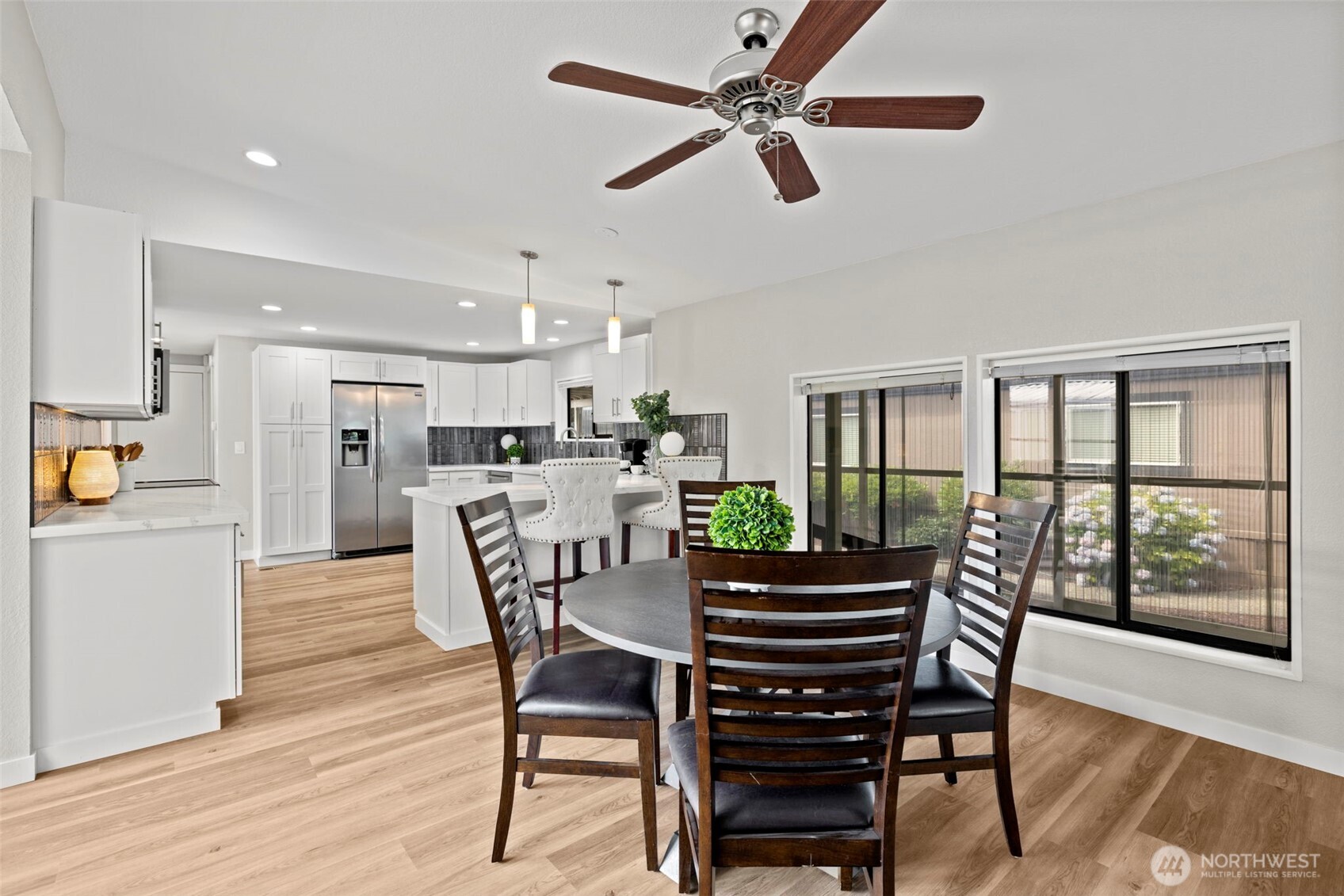 A variety of table sizes will fit in this space. Large windows are a wonderful backdrop for this space. Blinds are up in the photo.