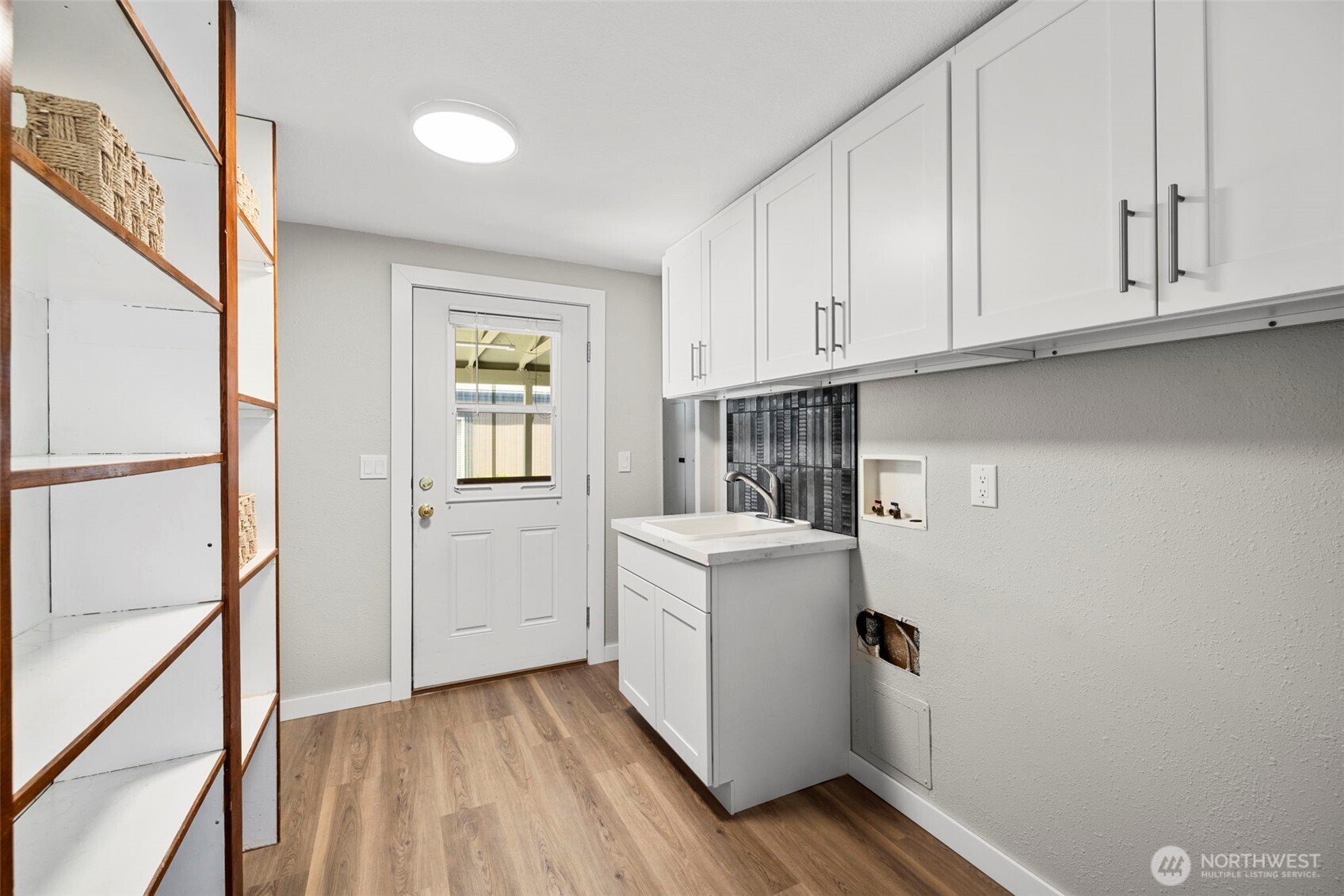 Laundry/pass through mud room with storage shelving and new cabinetry plus vanity sink. Location for your washer and dryer.