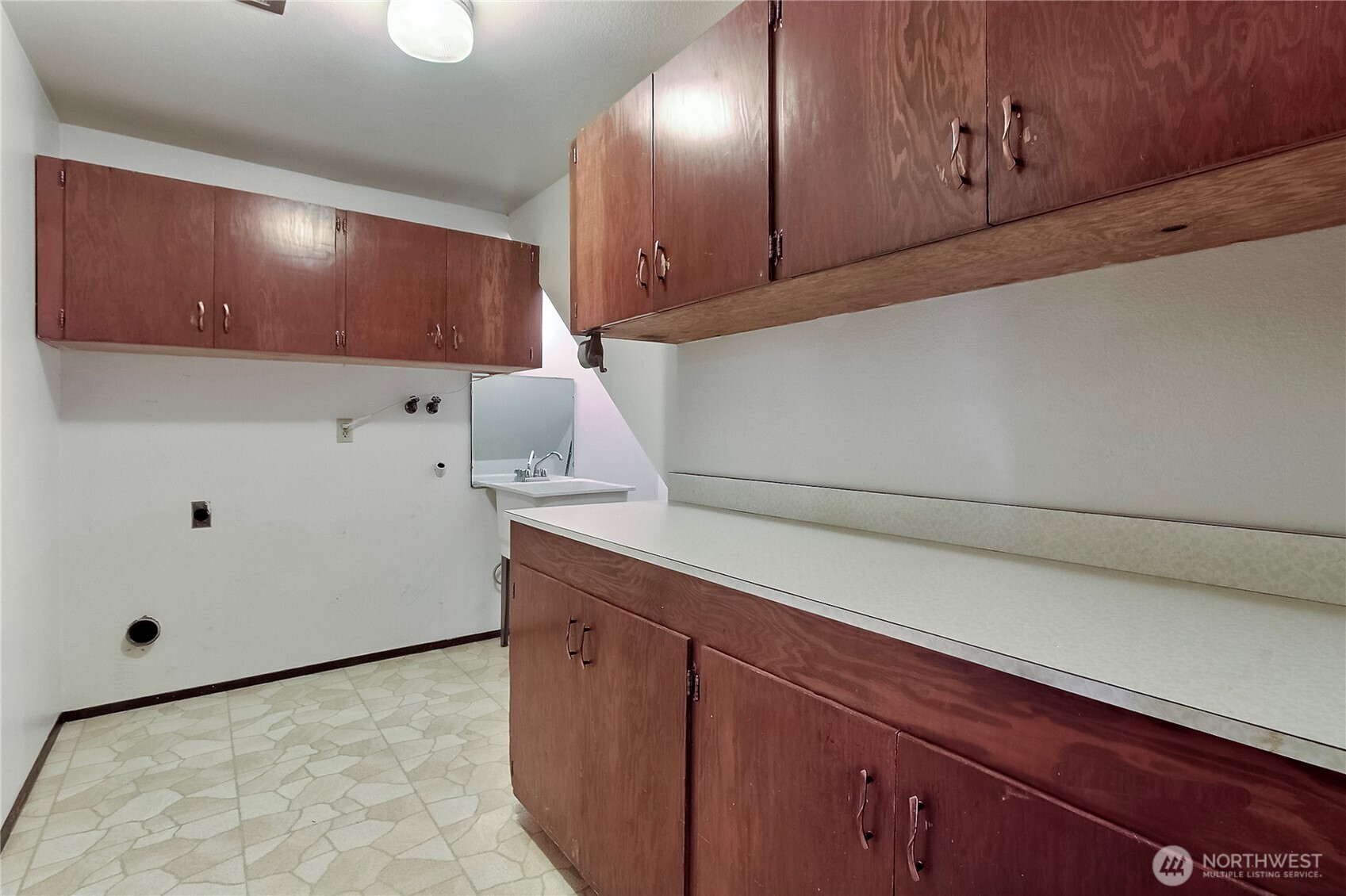 Laundry room with a utility sink and lots of storage cabinets.