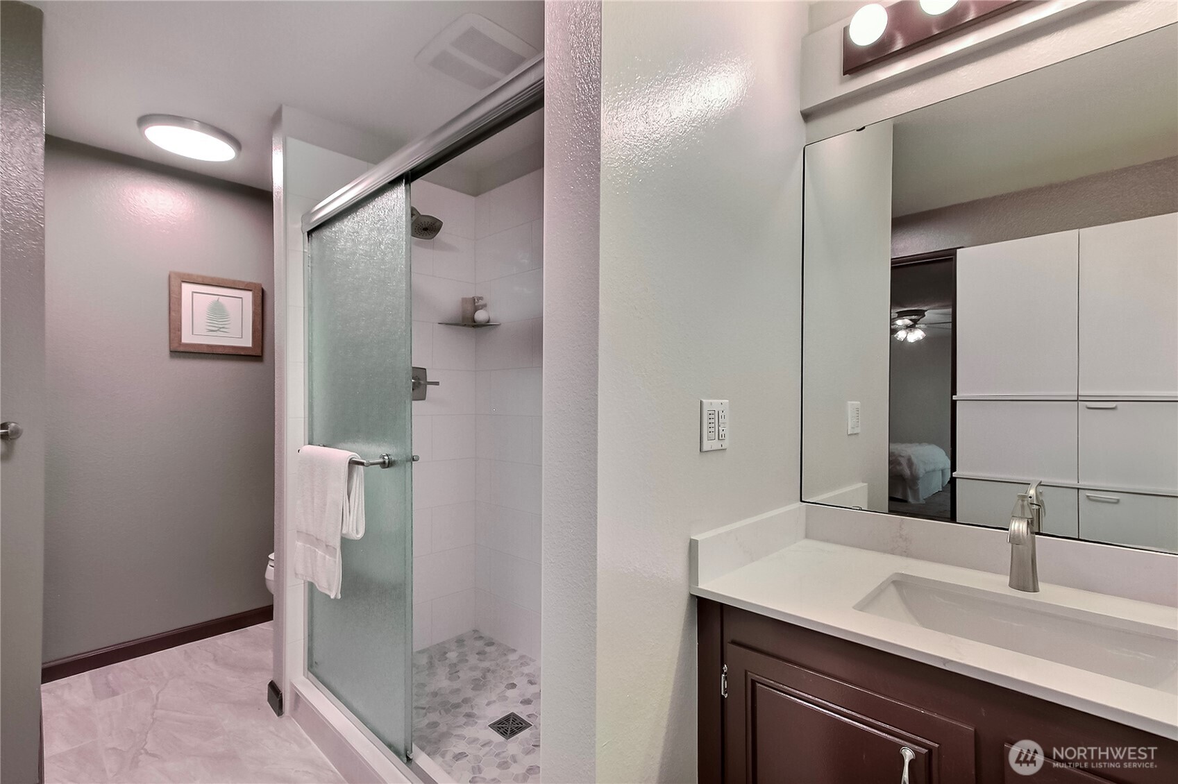 Primary bath has just been remodeled with a new shower, tile flooring and a quartz countertop.