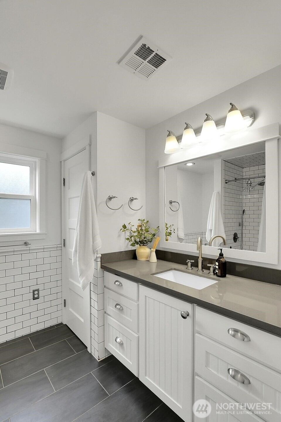 Half tiled wall and quartz counter tops in the primary bathroom.