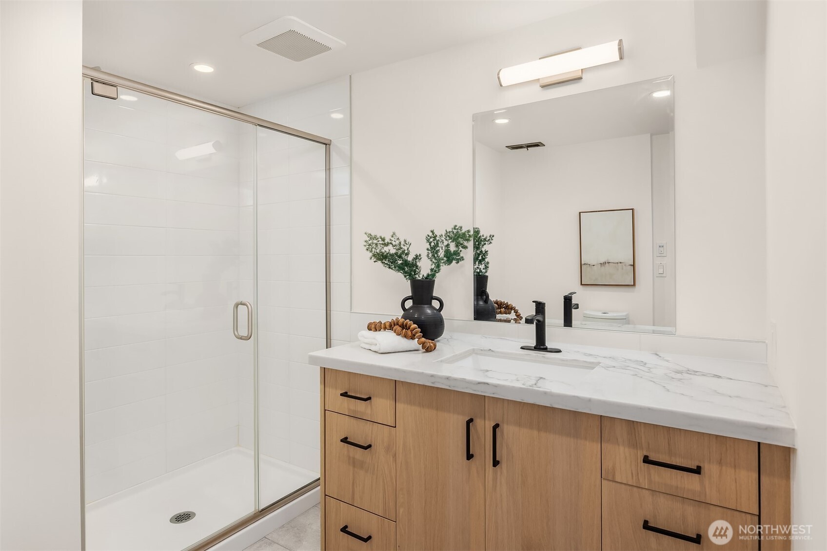 The lower-level bathroom was renovated in 2024 with a new vanity and counter, frameless glass shower door, and modern lighting and fixtures