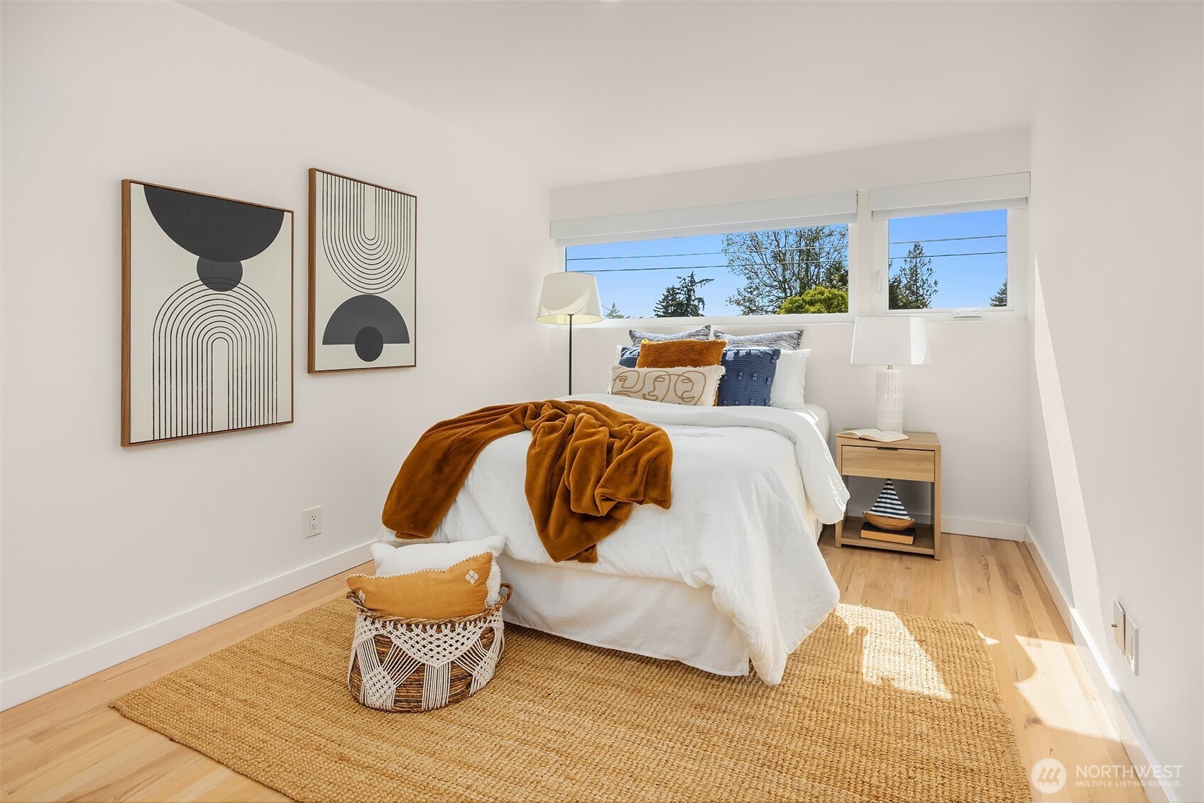The first bedroom off the hallway is bright and airy, with west-facing windows that capture beautiful city views and afternoon light.