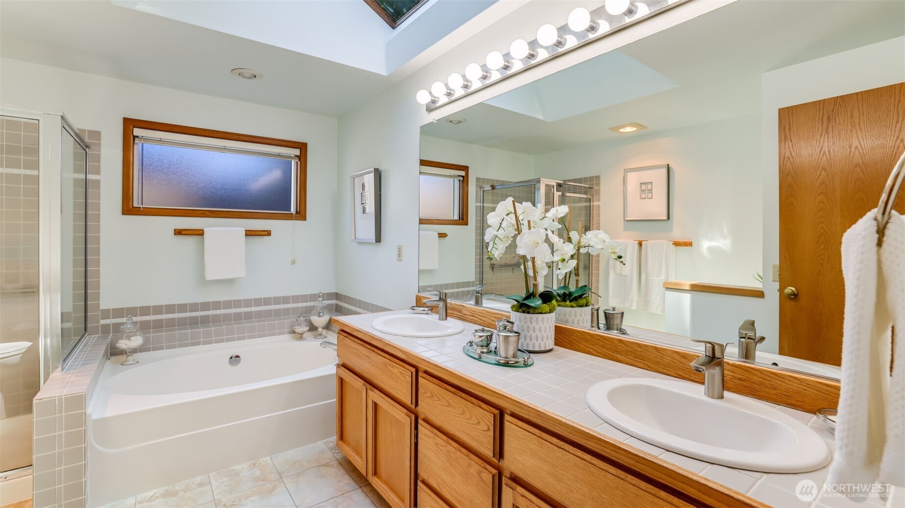 The primary bath has it all.  2 sinks, tile counters and upgraded tile flooring.  A walk-in closet, soaking tub and a spacious shower.  The oversized skylight lets sun stream in.